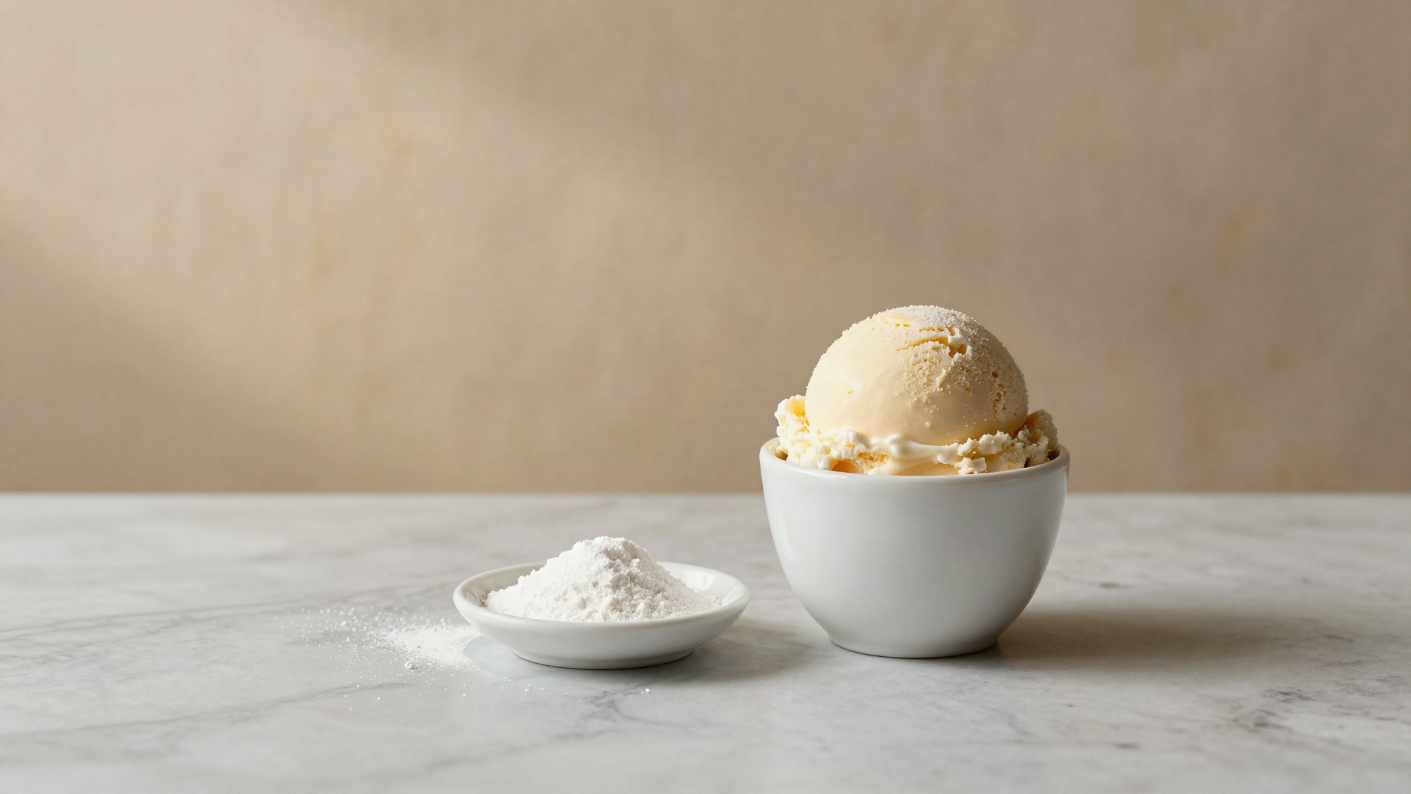 A scoop of gelato beside a dish of fine white starch powder on a marble counter