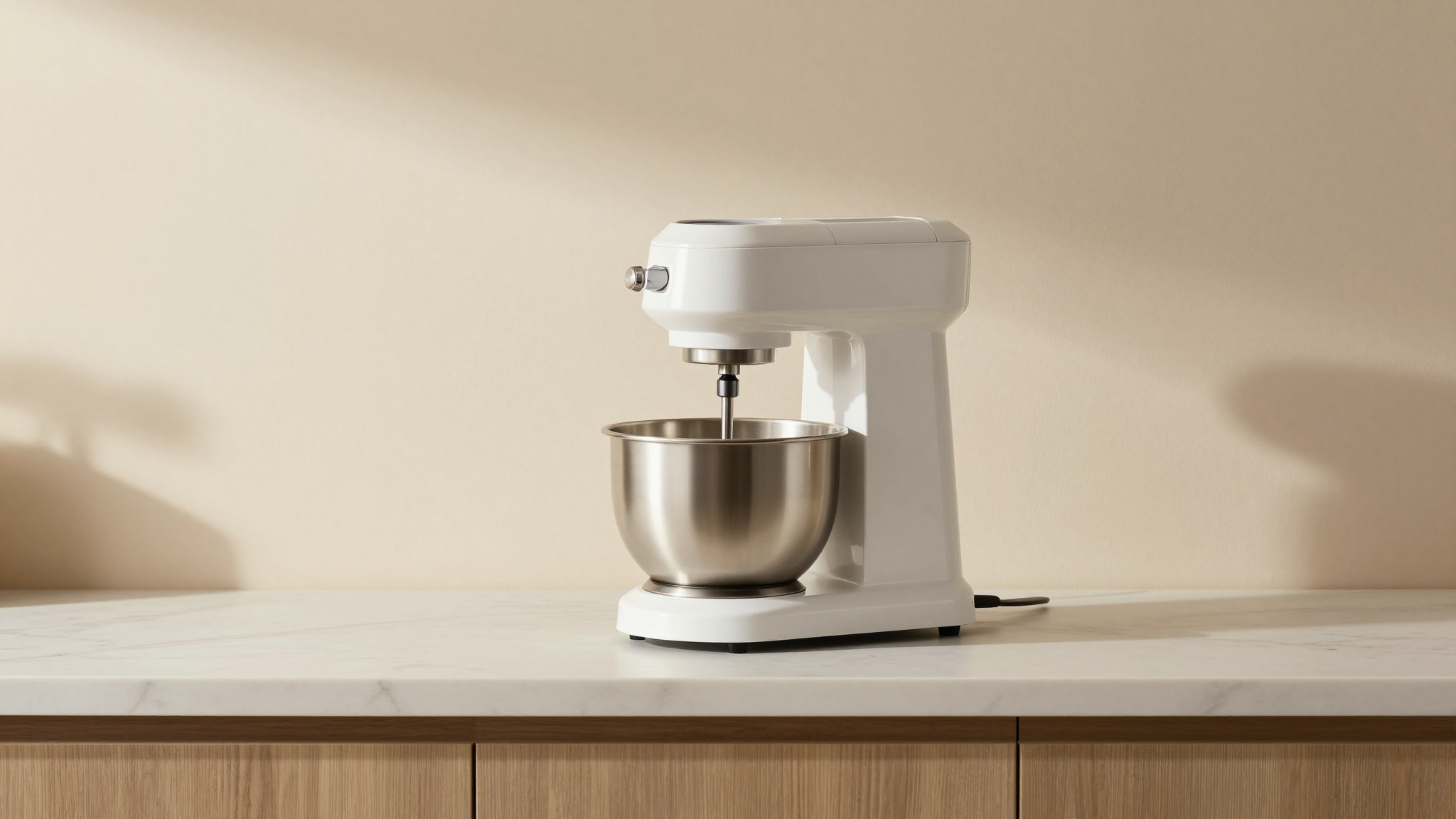 A sleek countertop italian gelato machine in stainless steel and white plastic running on a kitchen counter showing the mixing bowl with churning paddle