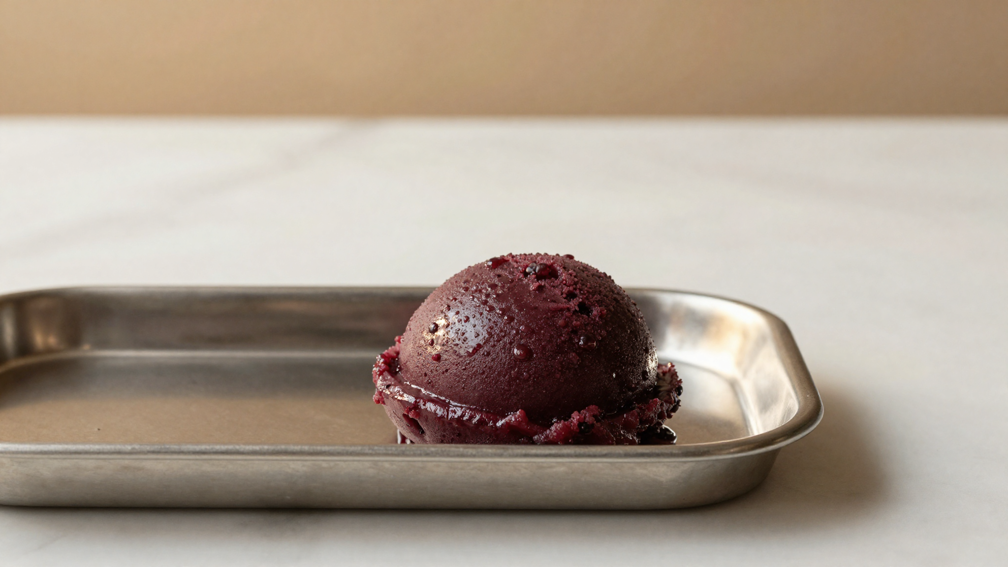 A quenelle of blackberry sorbetto scooped from a tray