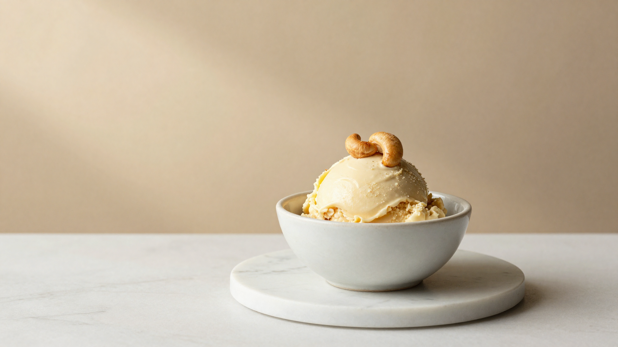 A finished quenelle of creamy vegan cashew milk gelato garnished with a toasted cashew
