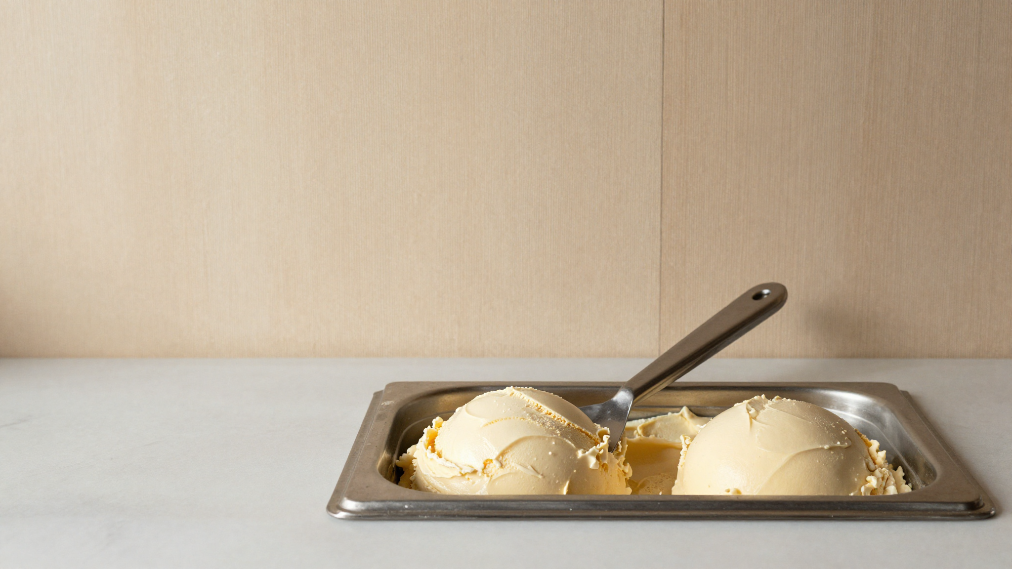 Finished chestnut gelato in a stainless tub with a spade