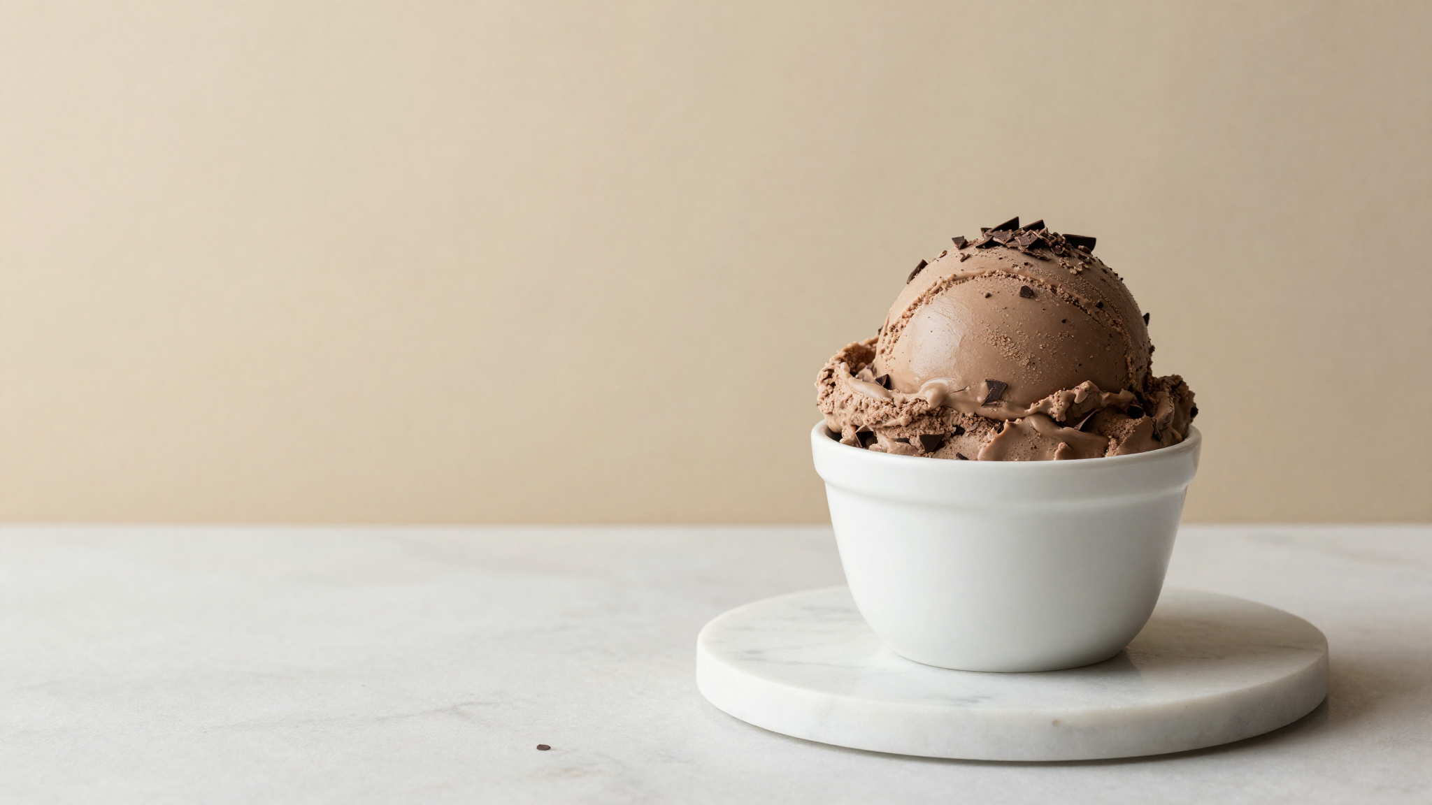 Dark chocolate chips showing subtle whitish bloom next to glossy unbloomed chips on marble