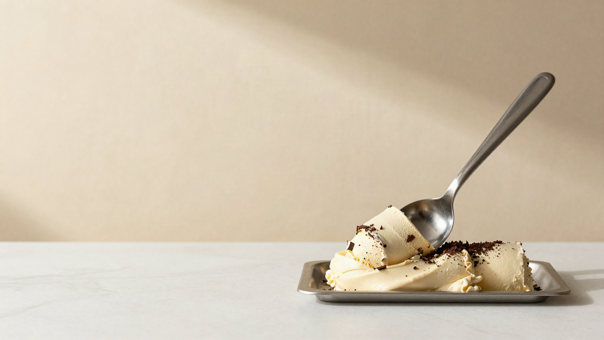 A stainless steel spade resting on a curl of chocolate chip gelato lifted from a display pan