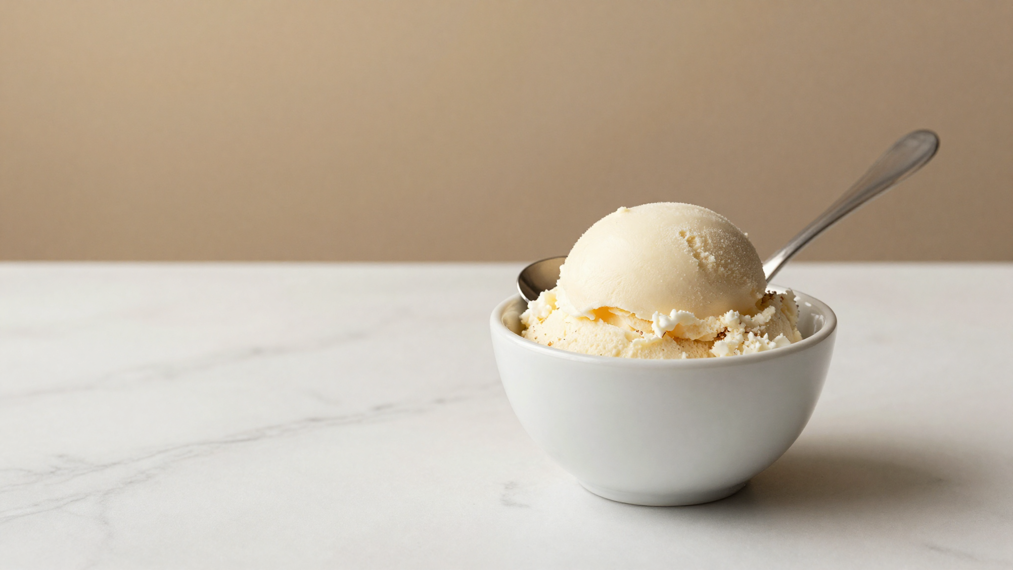 Spoonful of pale coconut gelato showing a dense, smooth surface in a ceramic cup