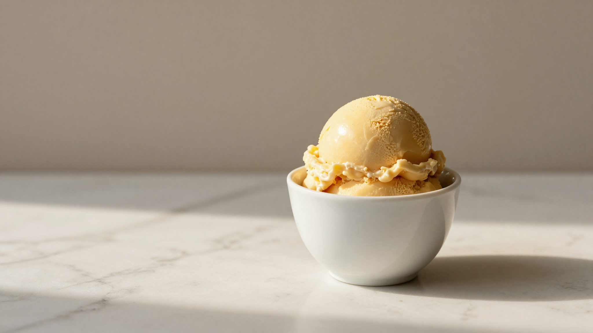 A single golden scoop of crema all'uovo custard gelato in a ceramic cup