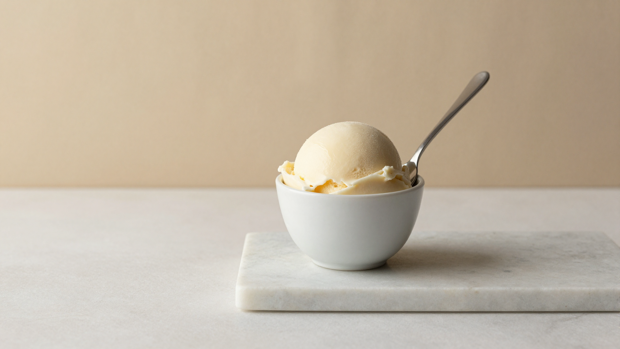 Dense smooth scoop of Italian gelato in a white ceramic cup with a spoon