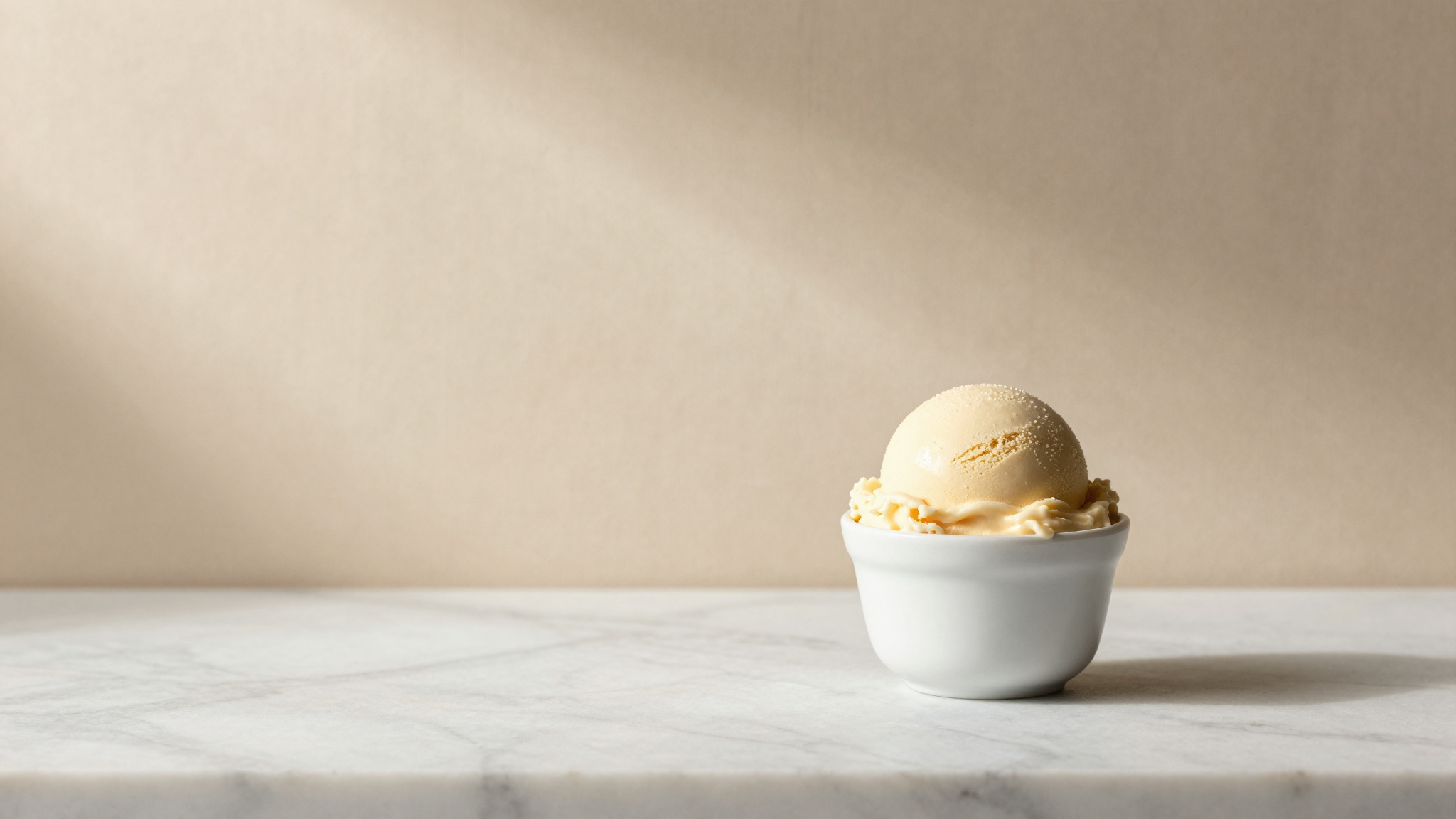 A scoop of italian gelato in a small ceramic cup on marble, conceptual still life evoking freezing