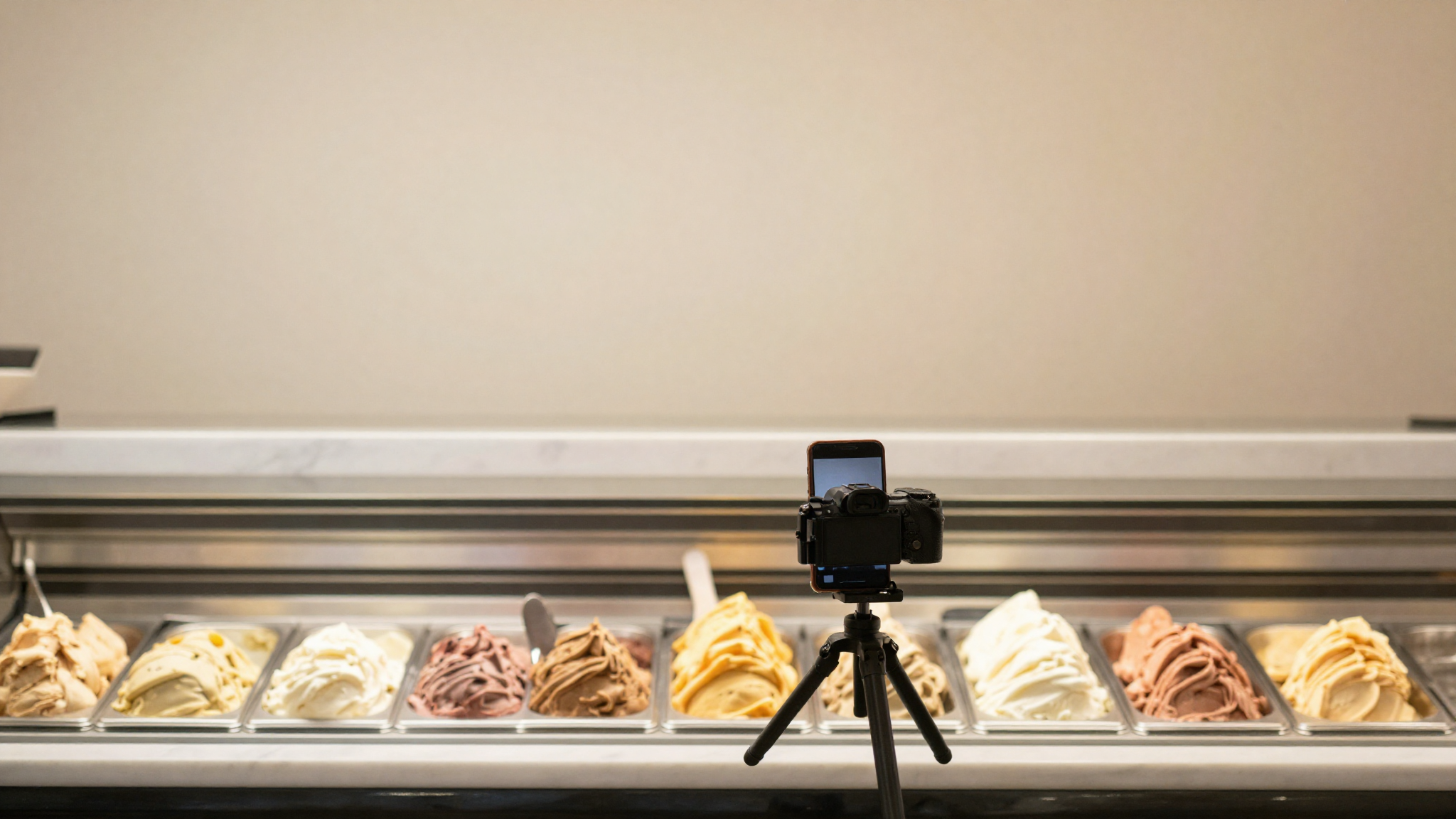A smartphone on a tripod photographing a colorful gelato display in a bright gelateria