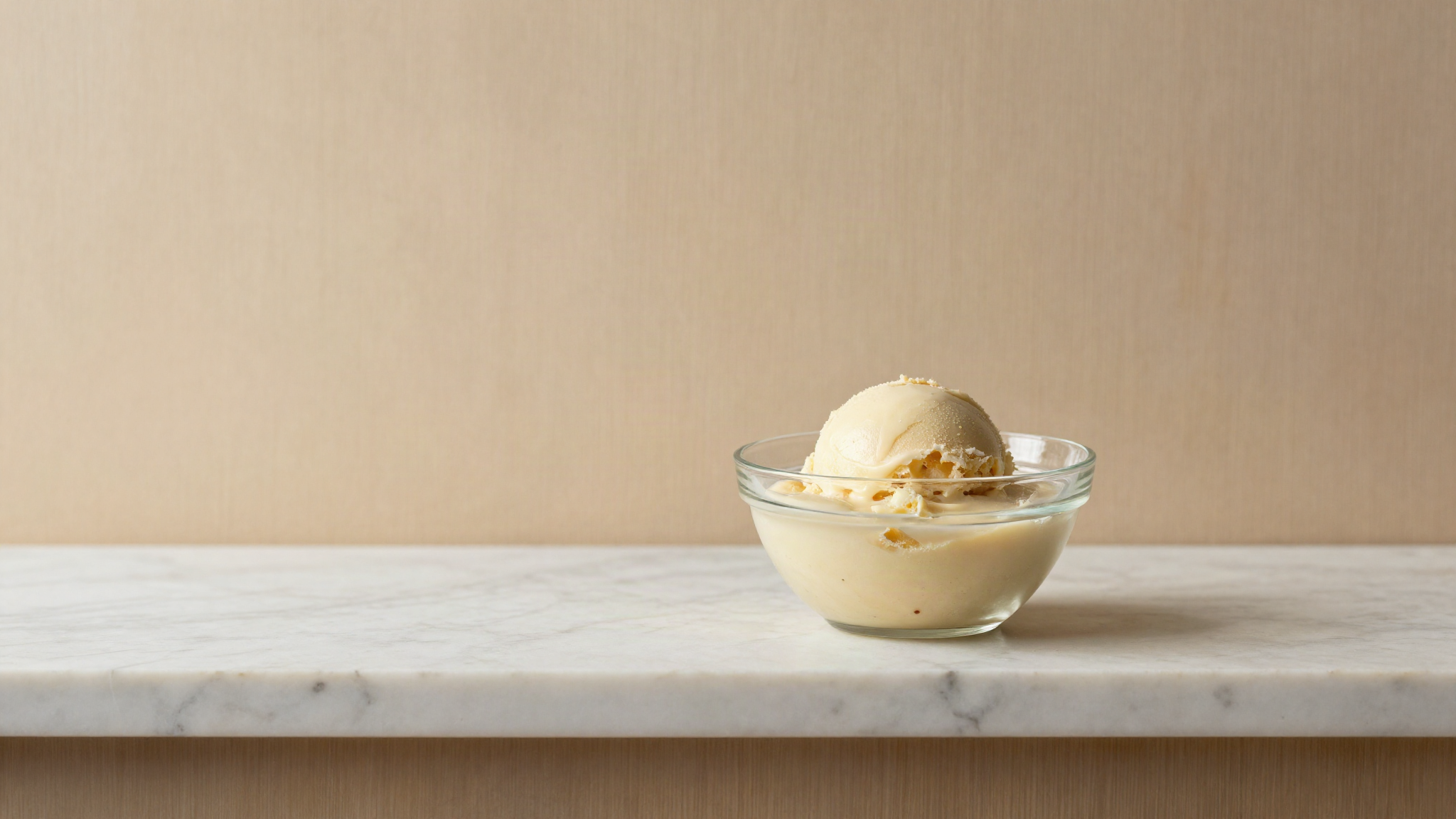 Covered glass bowl of pale gelato base ageing cold on a marble shelf