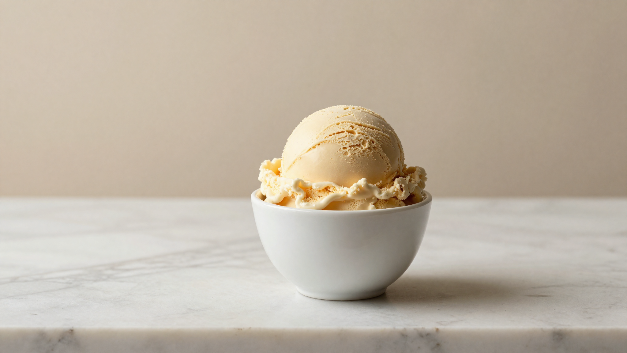 Dense scoop of italian gelato in a white ceramic cup on marble