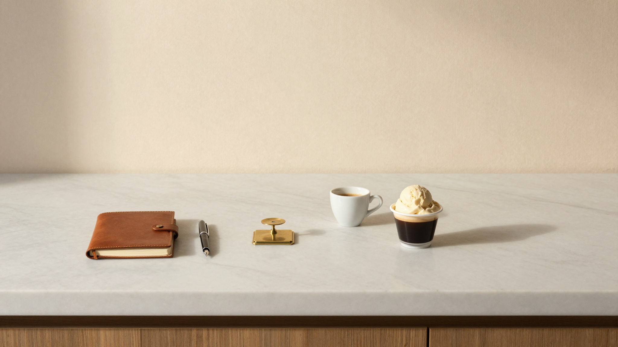 Pricing tools on a marble gelateria counter — notebook, fountain pen, scale, espresso, gelato cup