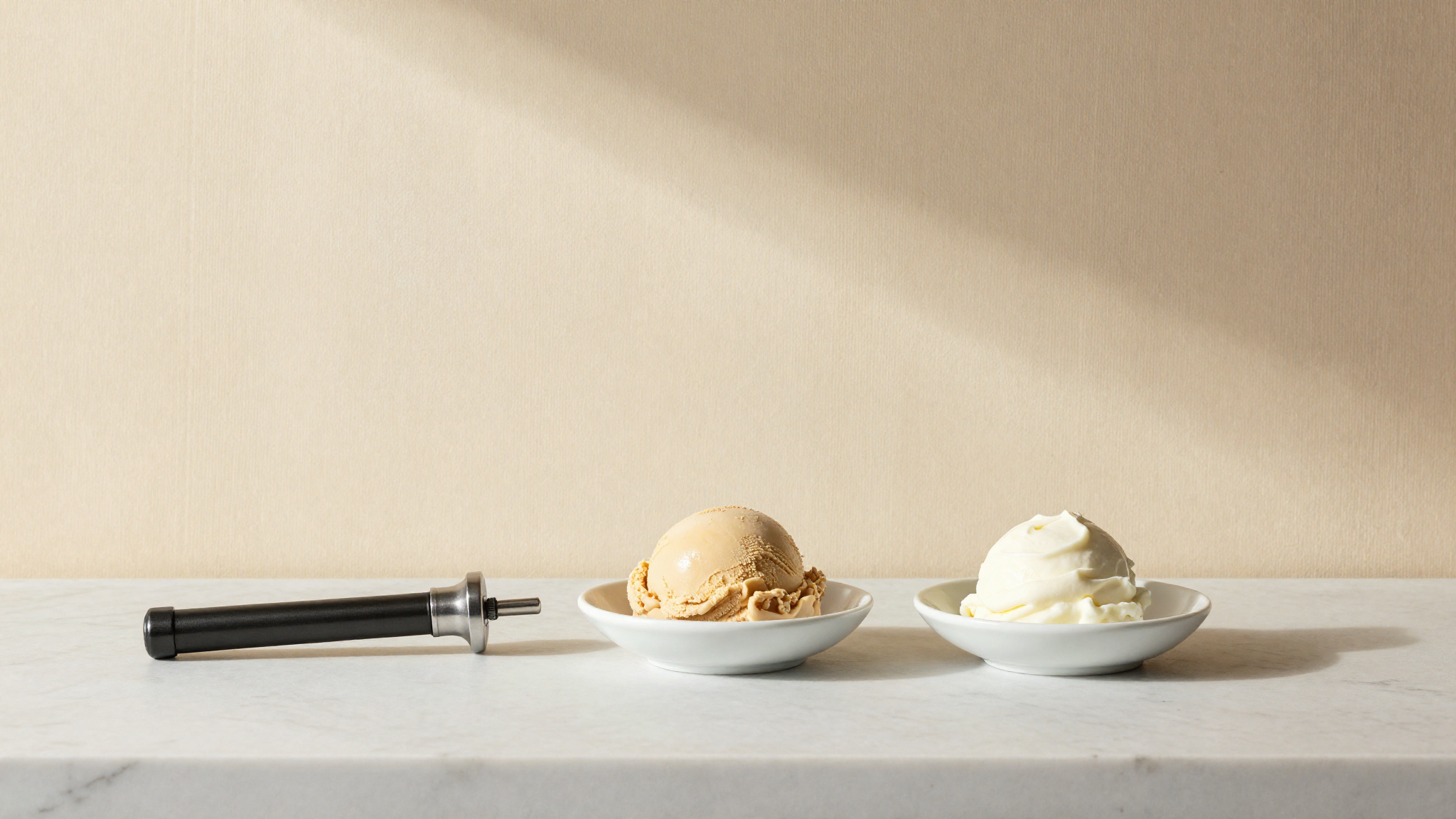 A chef thermometer probe between two small ceramic dishes of gelato and frozen yogurt on white marble