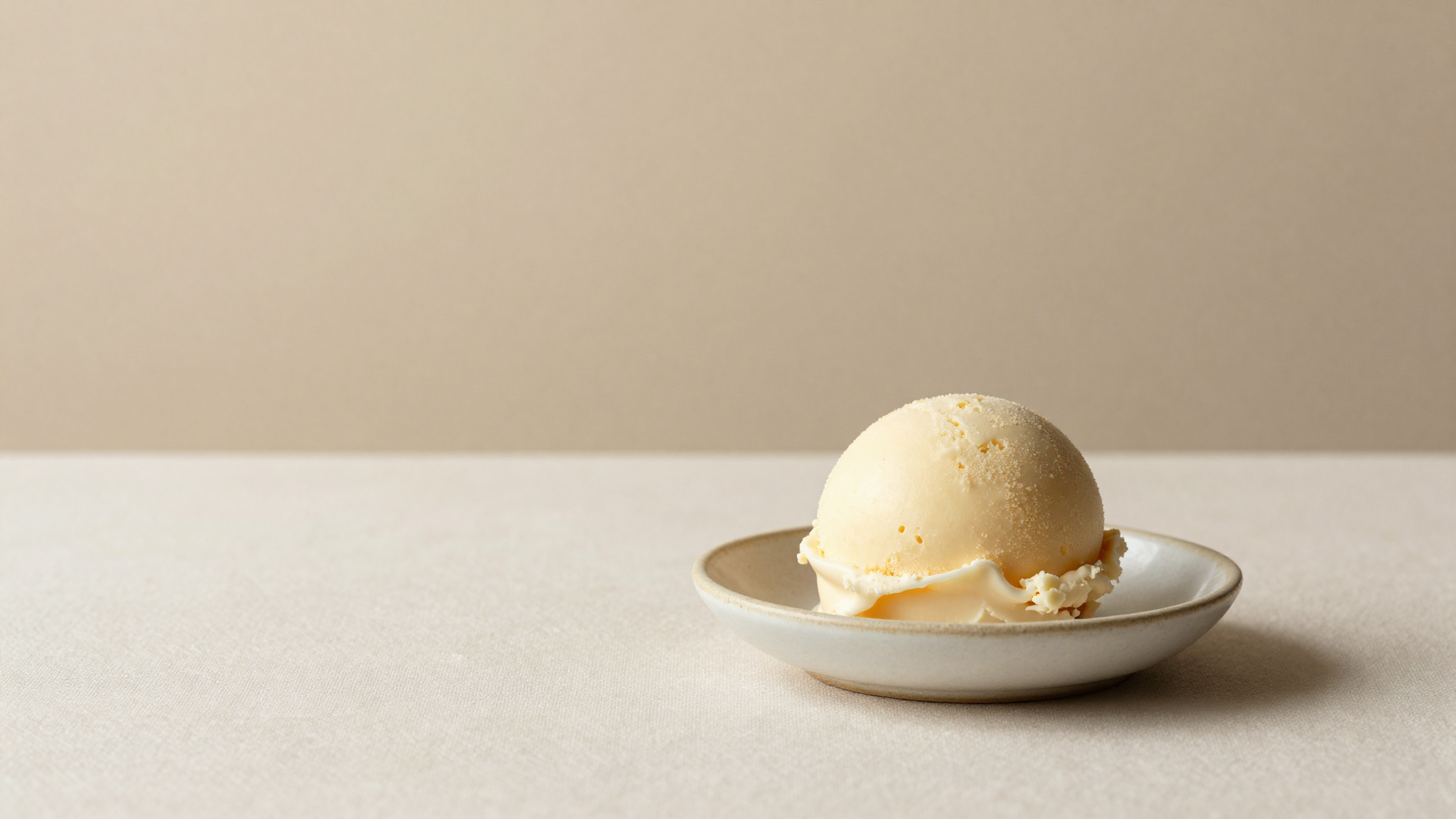 A fruit sherbet quenelle beside a creamy gelato scoop in two small ceramic dishes