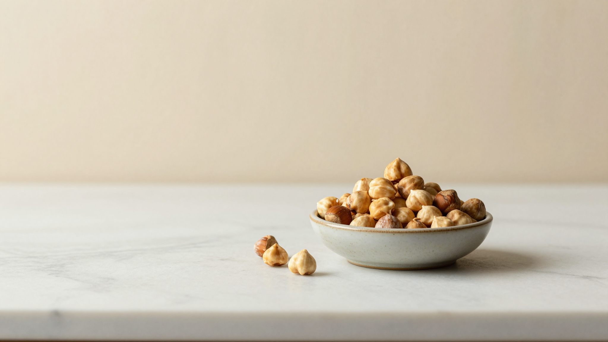 A small ceramic bowl piled with roasted piedmont hazelnuts