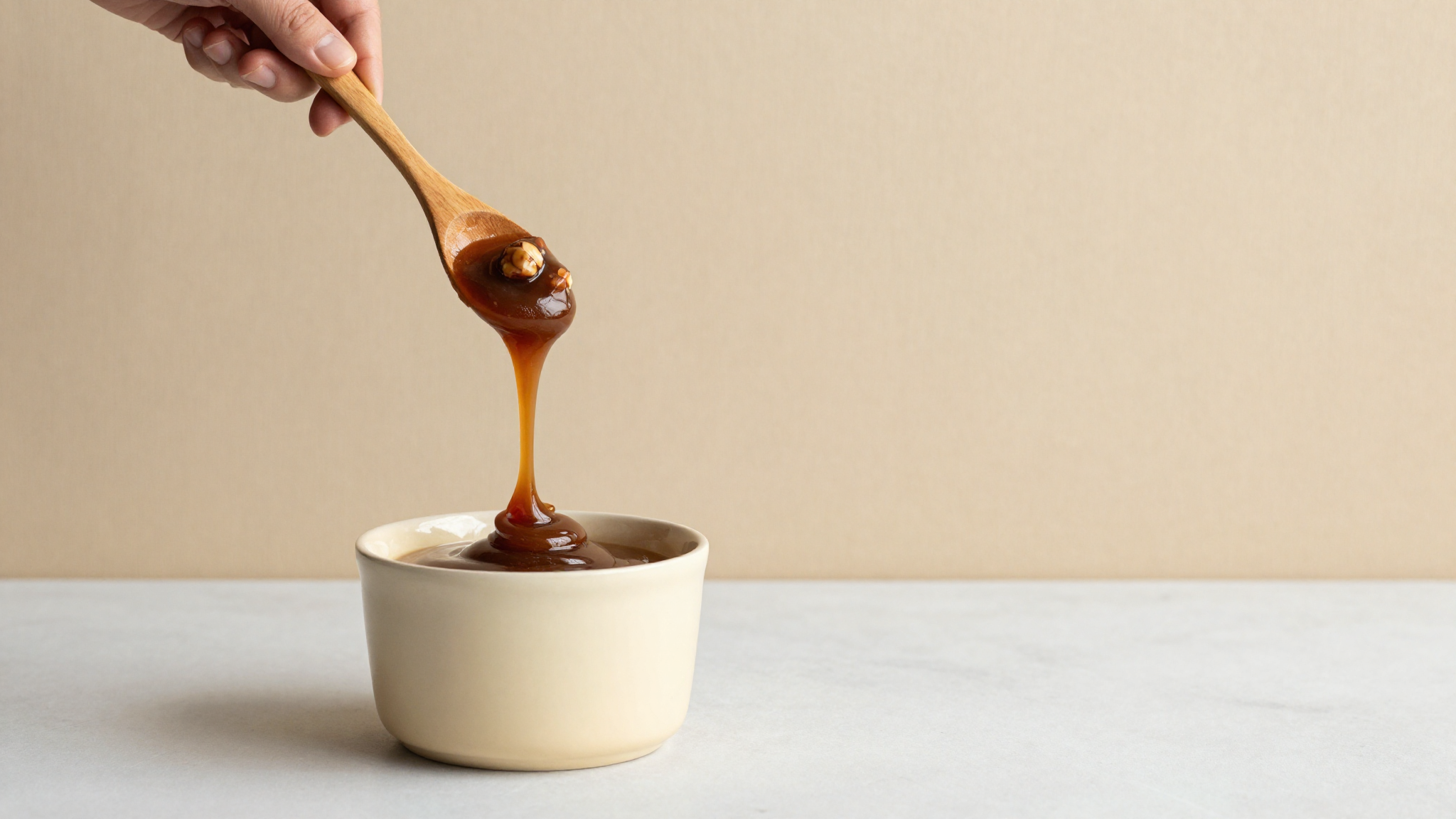 Cream being stirred with a ribbon of dark hazelnut paste suspended above