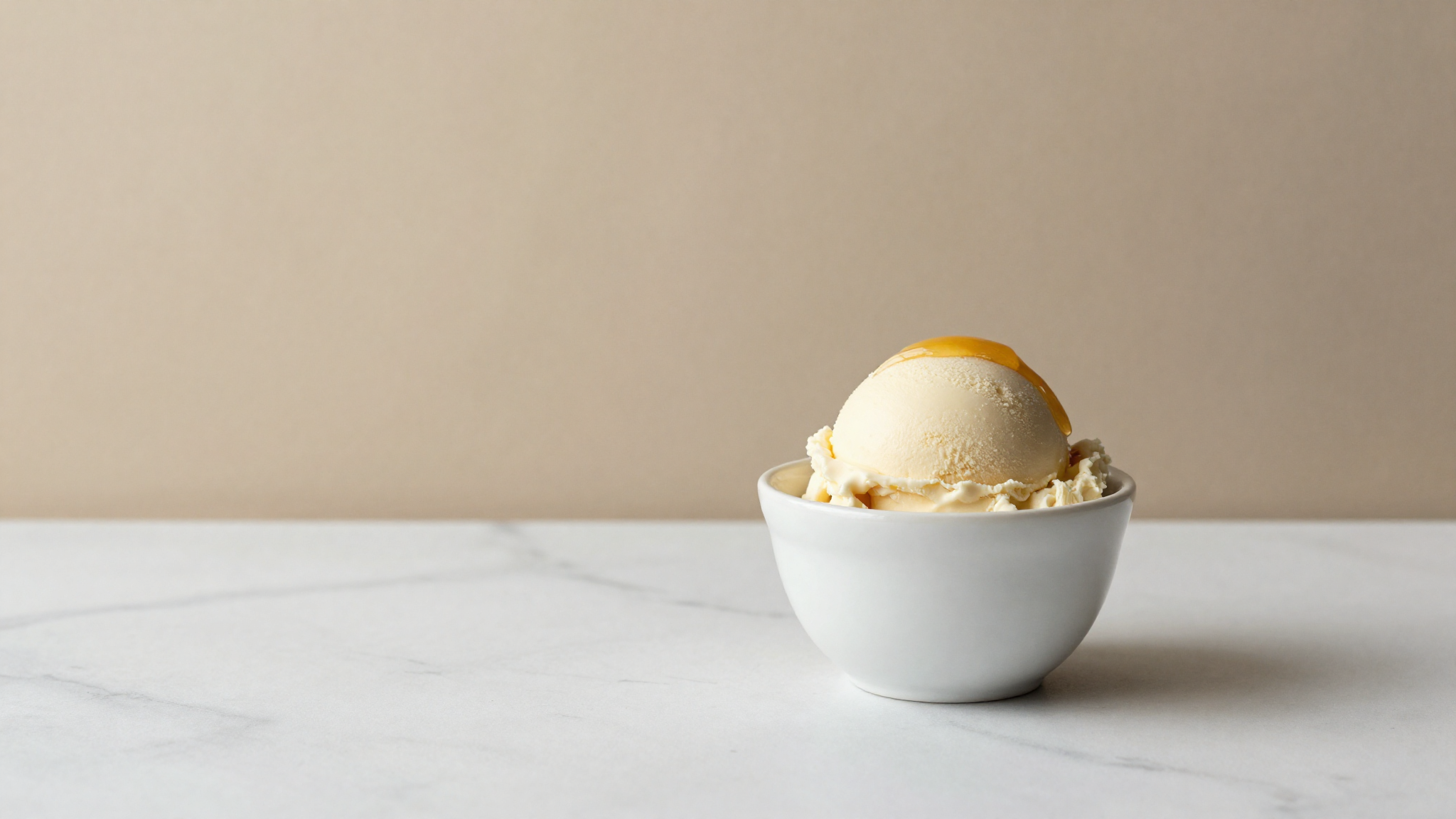 Finished pale goat milk gelato in a white cup with a honey drizzle