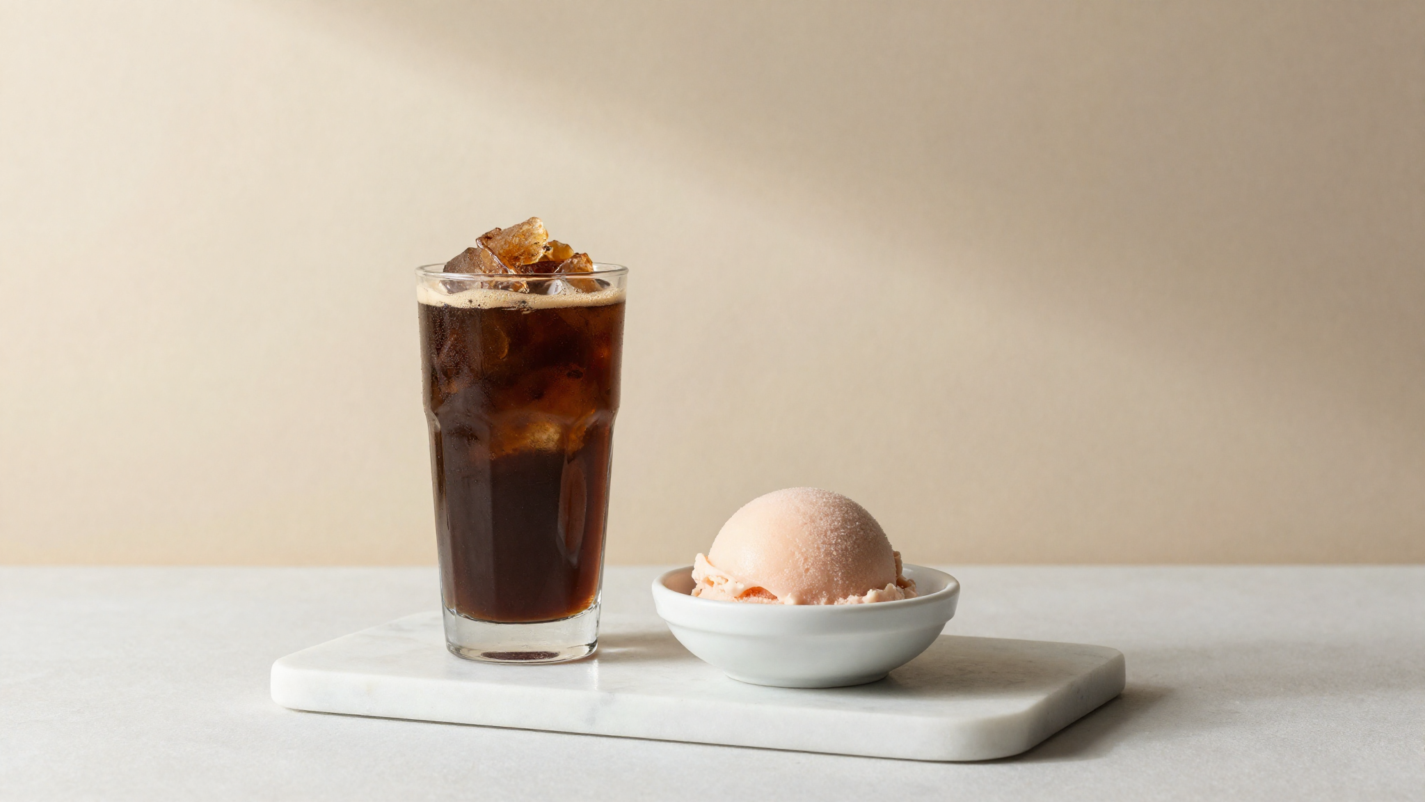 A tall glass of coffee granita and a scoop of fruit sorbet side by side