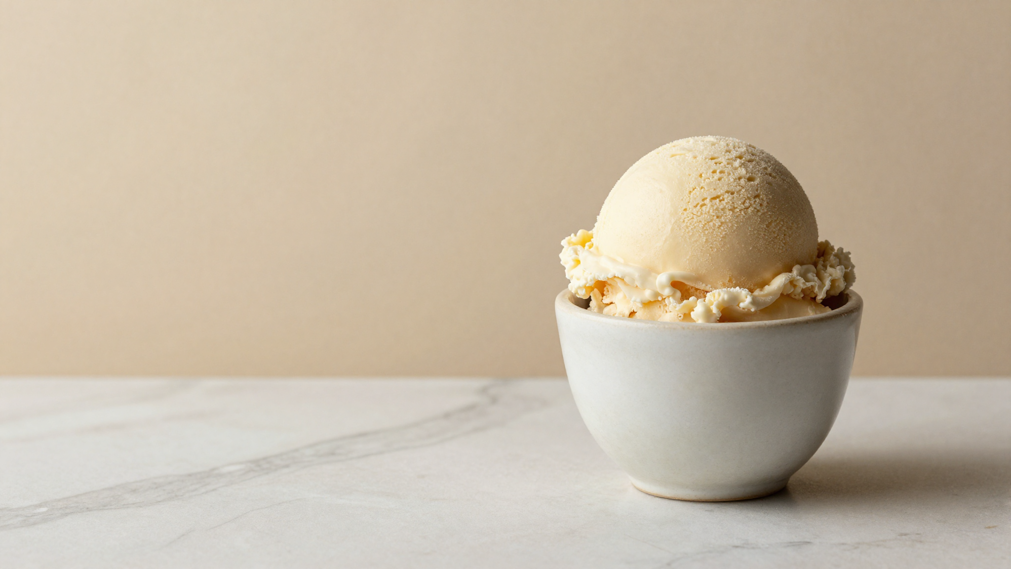 Dense smooth scoop of gelato in a ceramic cup on marble showing fine low-air texture