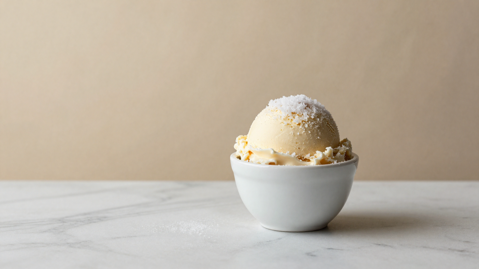 Scoop of italian gelato in a white ceramic cup on marble with fine surface frost