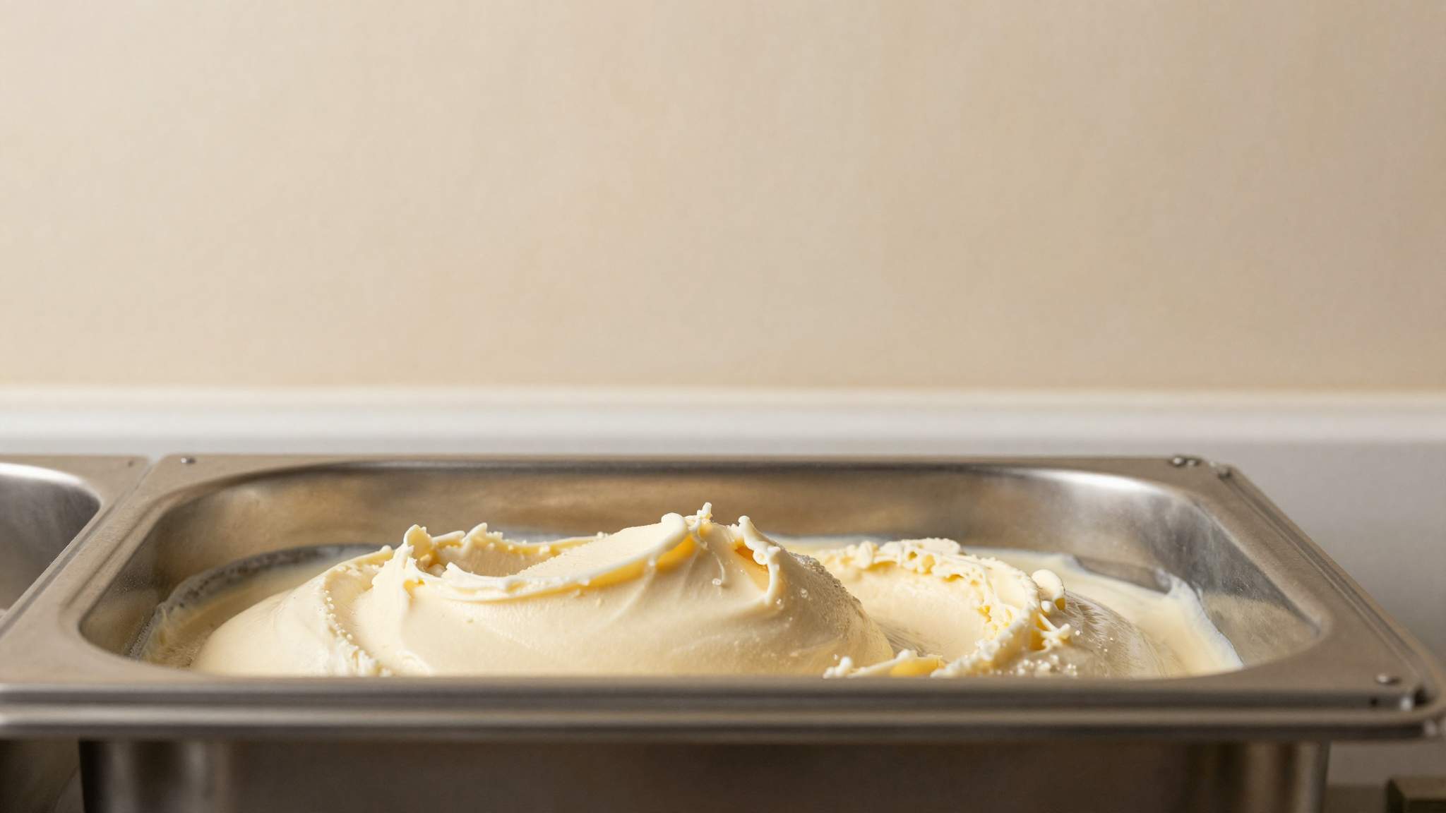 Pale tangy gelato mix churning in a stainless batch freezer