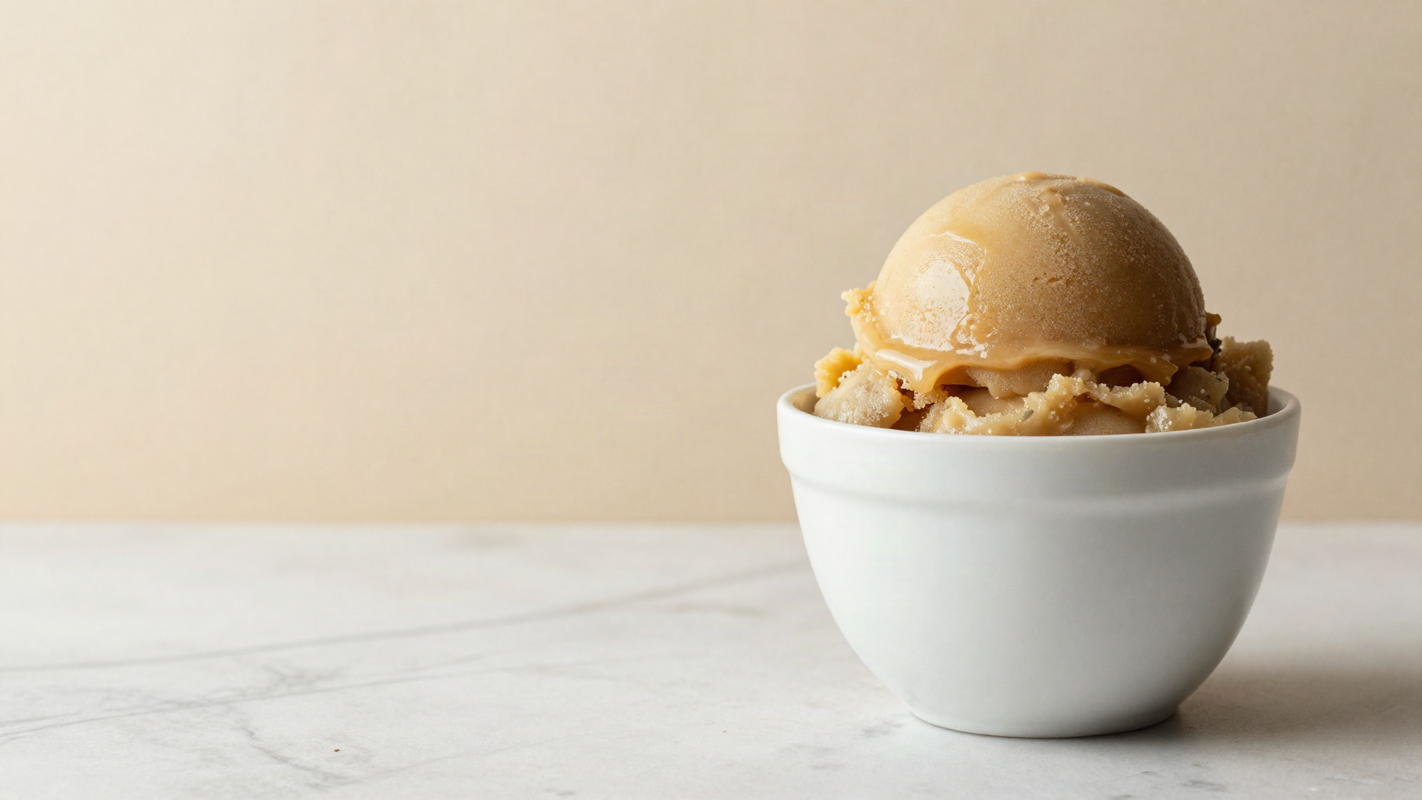 A scoop of glossy dense vegan fruit sorbet in a white ceramic cup showing smooth texture
