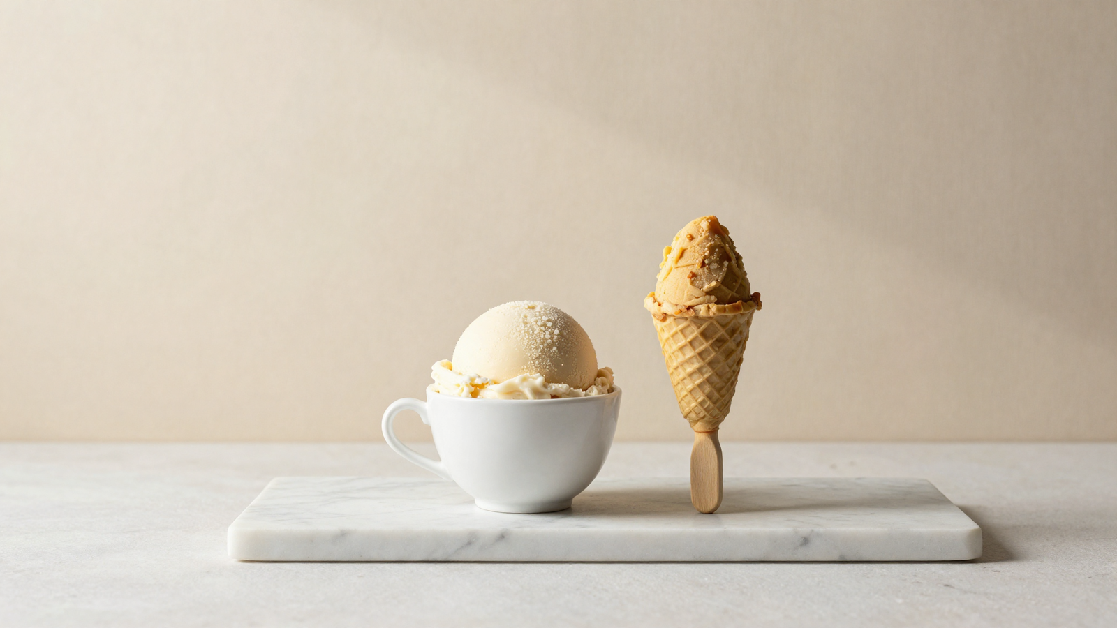 Italian gelato scoop and indian kulfi on a stick side by side on white marble