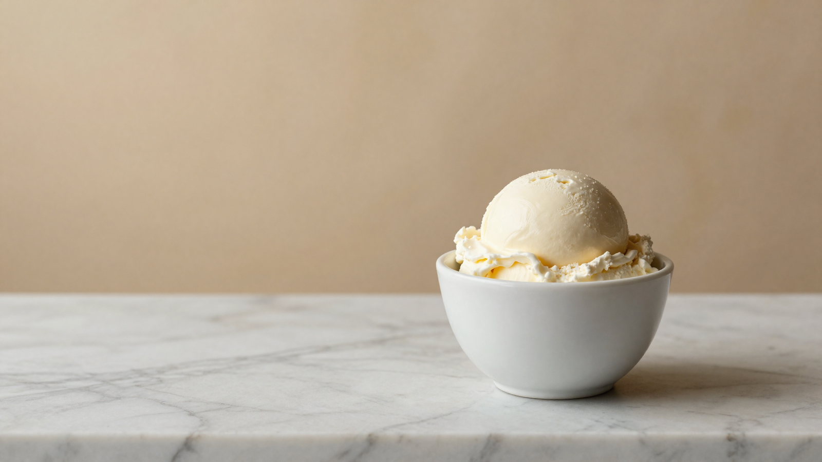 Smooth scoop of italian fior di latte gelato in a white ceramic cup on marble