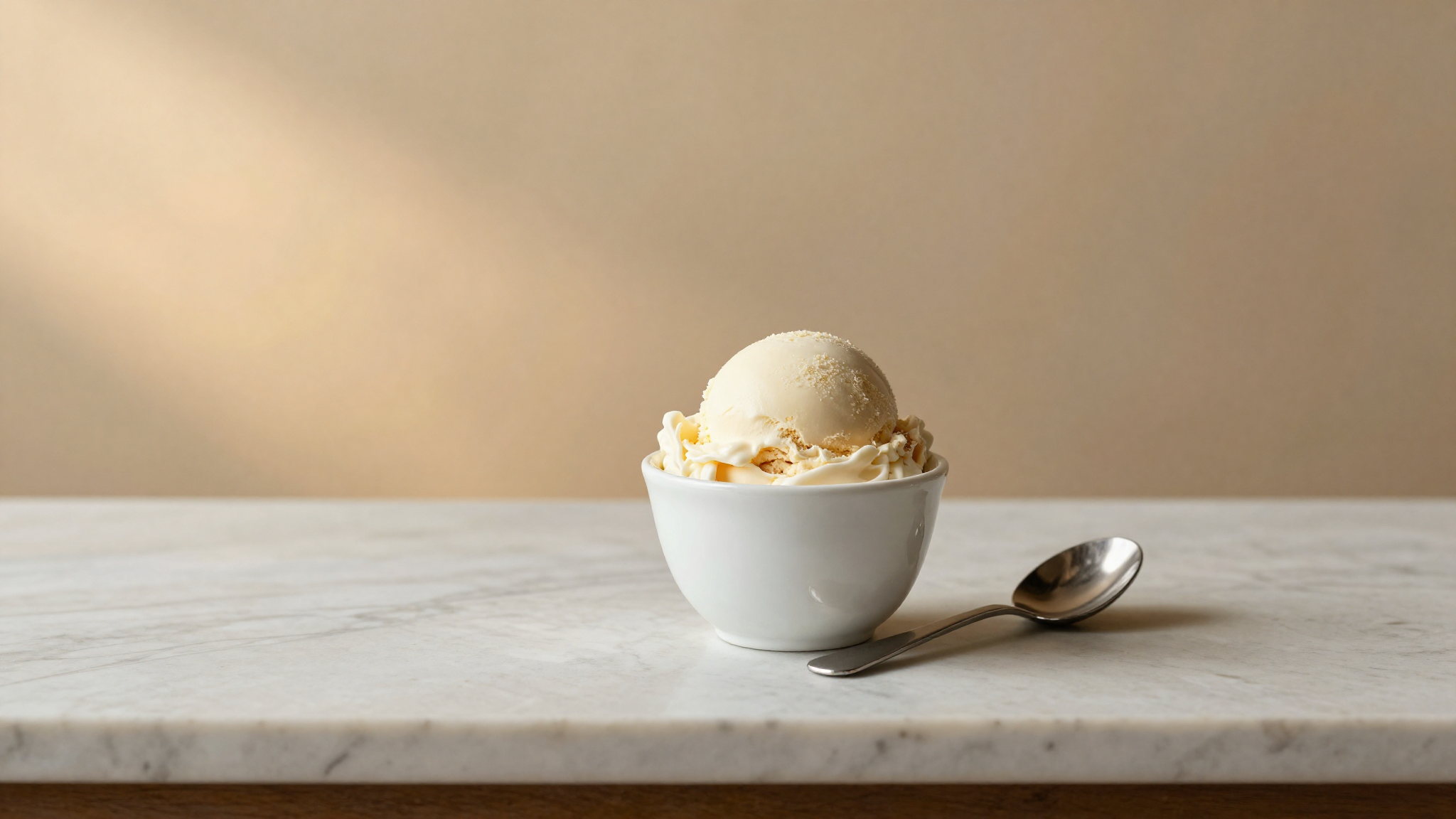 Finished lactose-free Italian gelato in a white ceramic cup on marble with a mini paddle