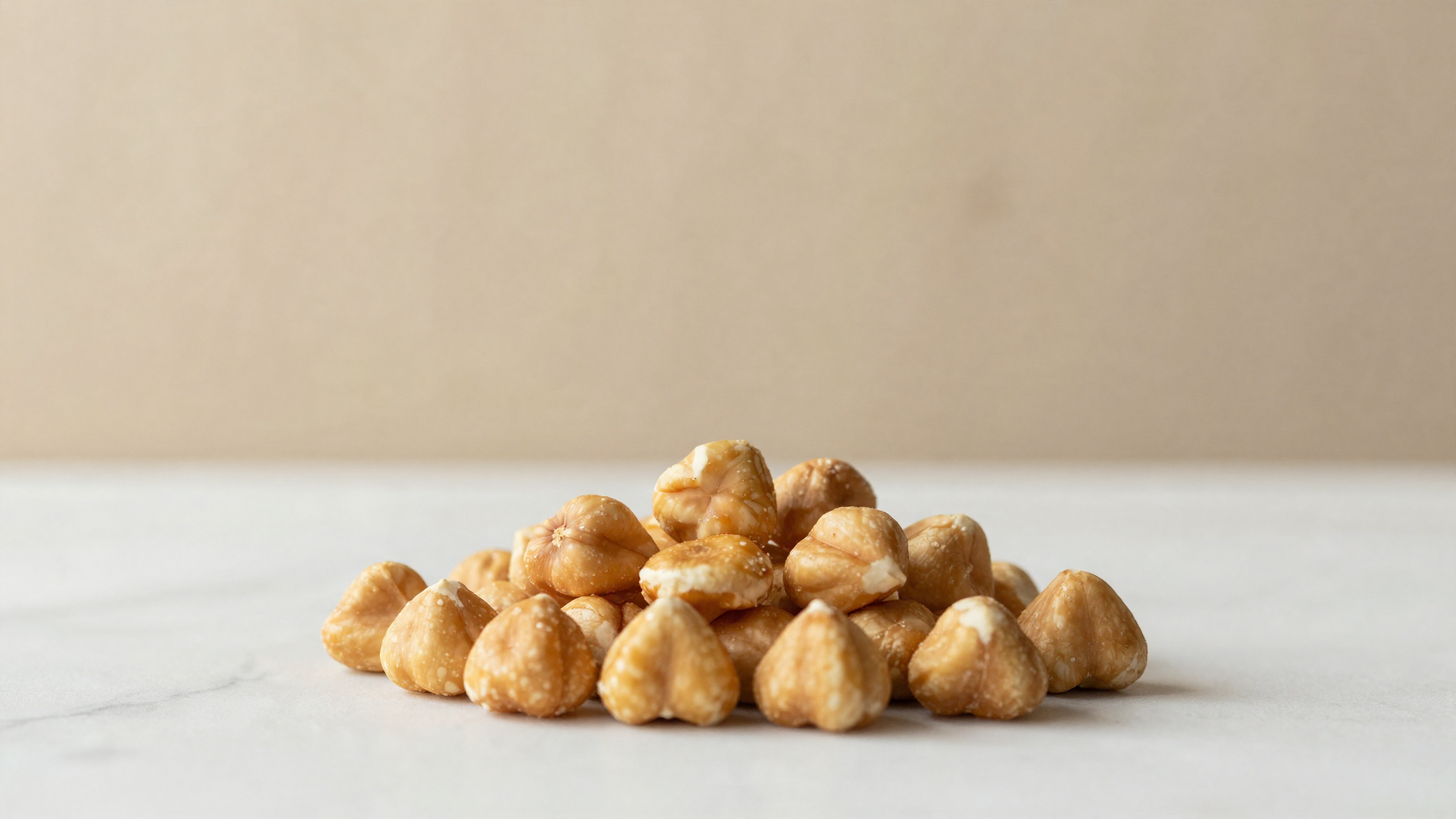 Freshly roasted hazelnuts with glossy golden-brown skins on marble