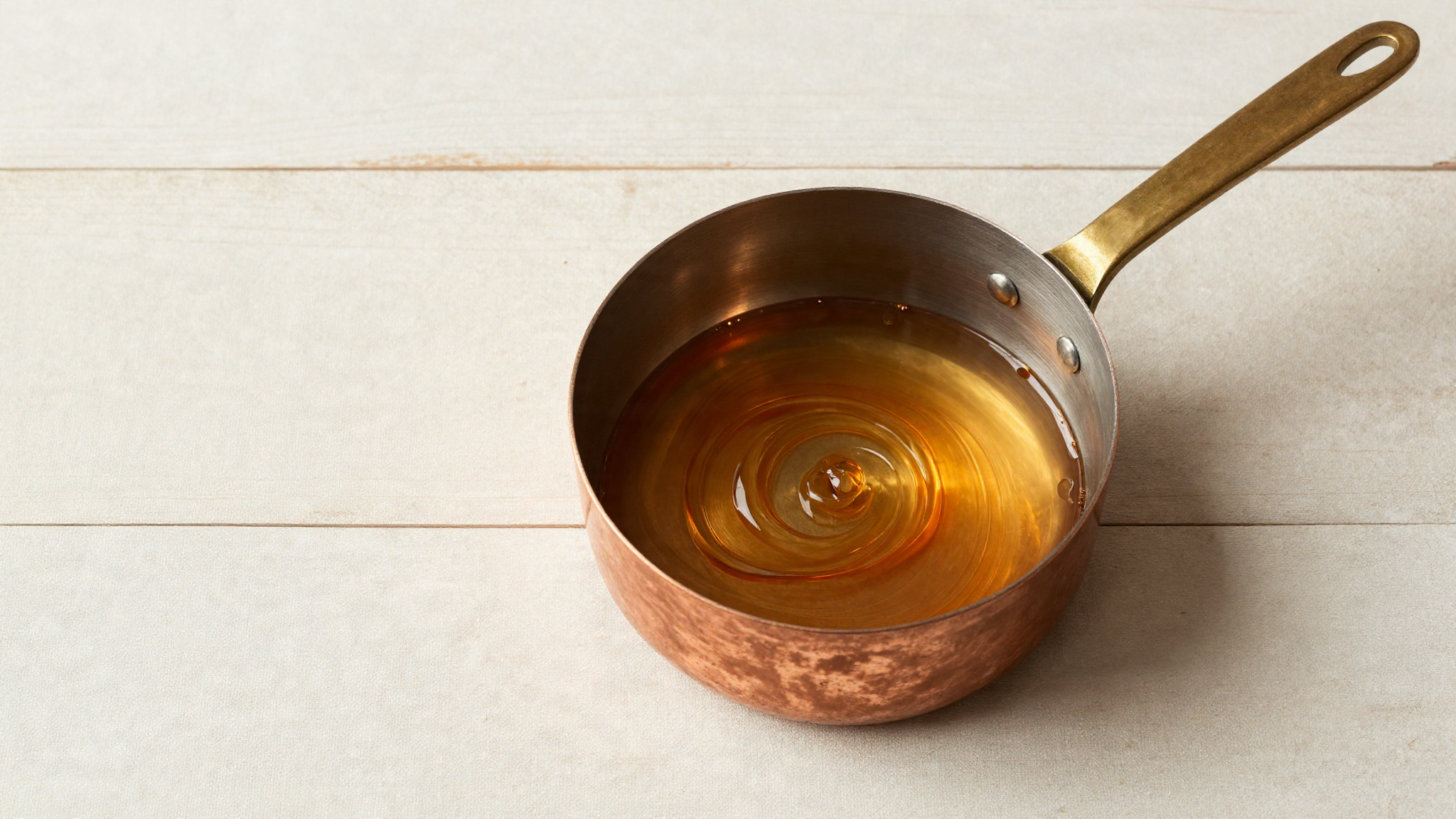 A copper saucepan of amber molten caramel as sugar caramelizes to deep gold