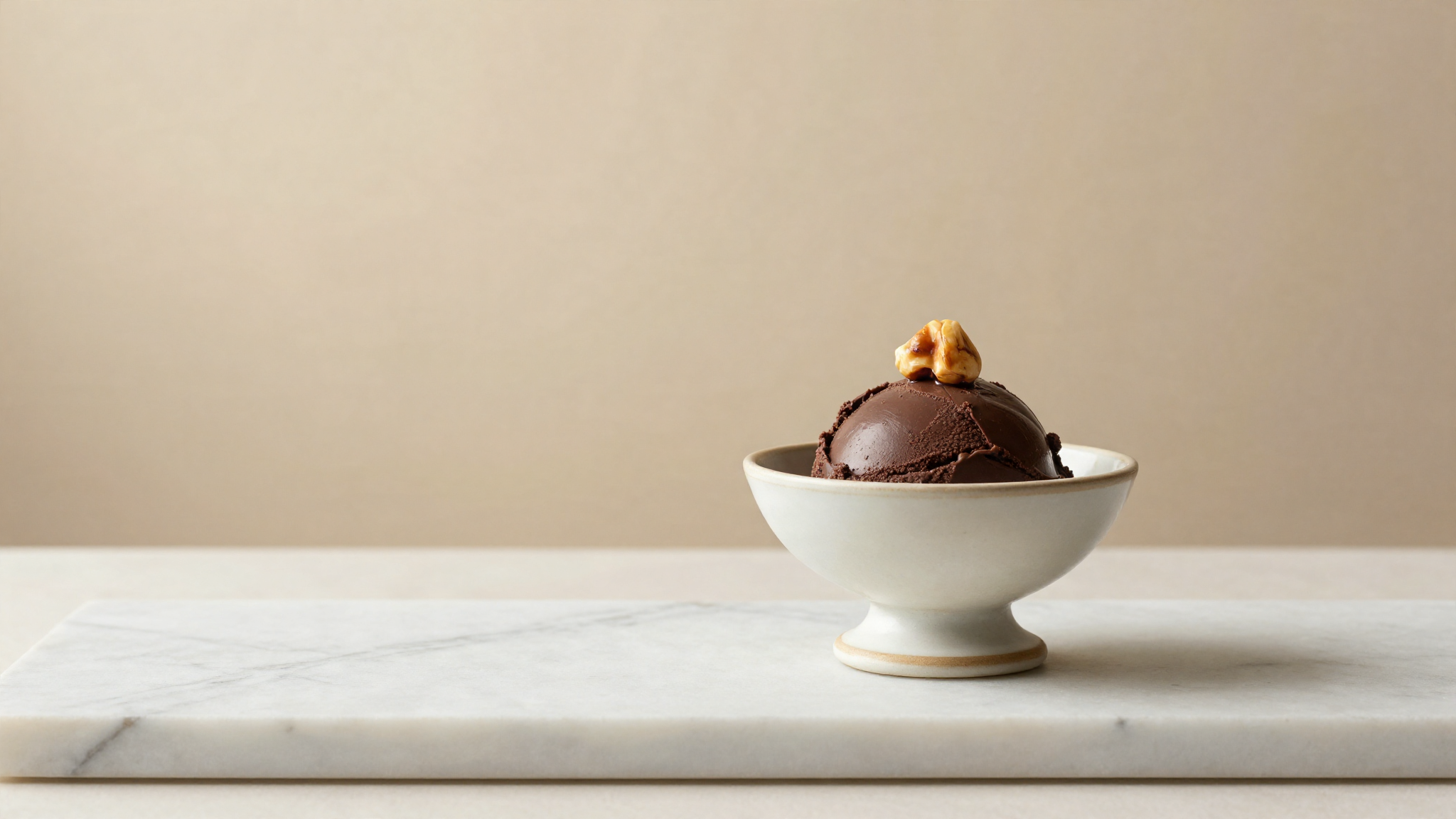 A refined serving of dark chocolate gelato garnished with a roasted hazelnut