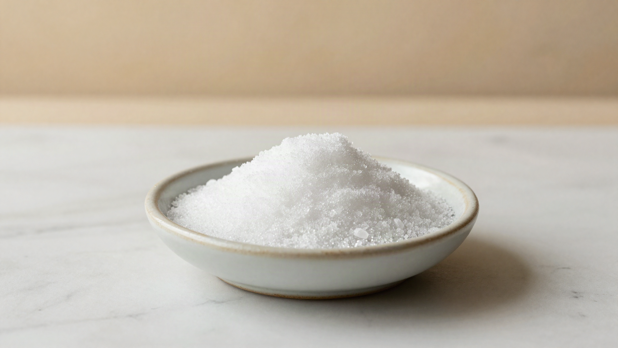 White crystalline maltitol in a small ceramic dish on a marble bench