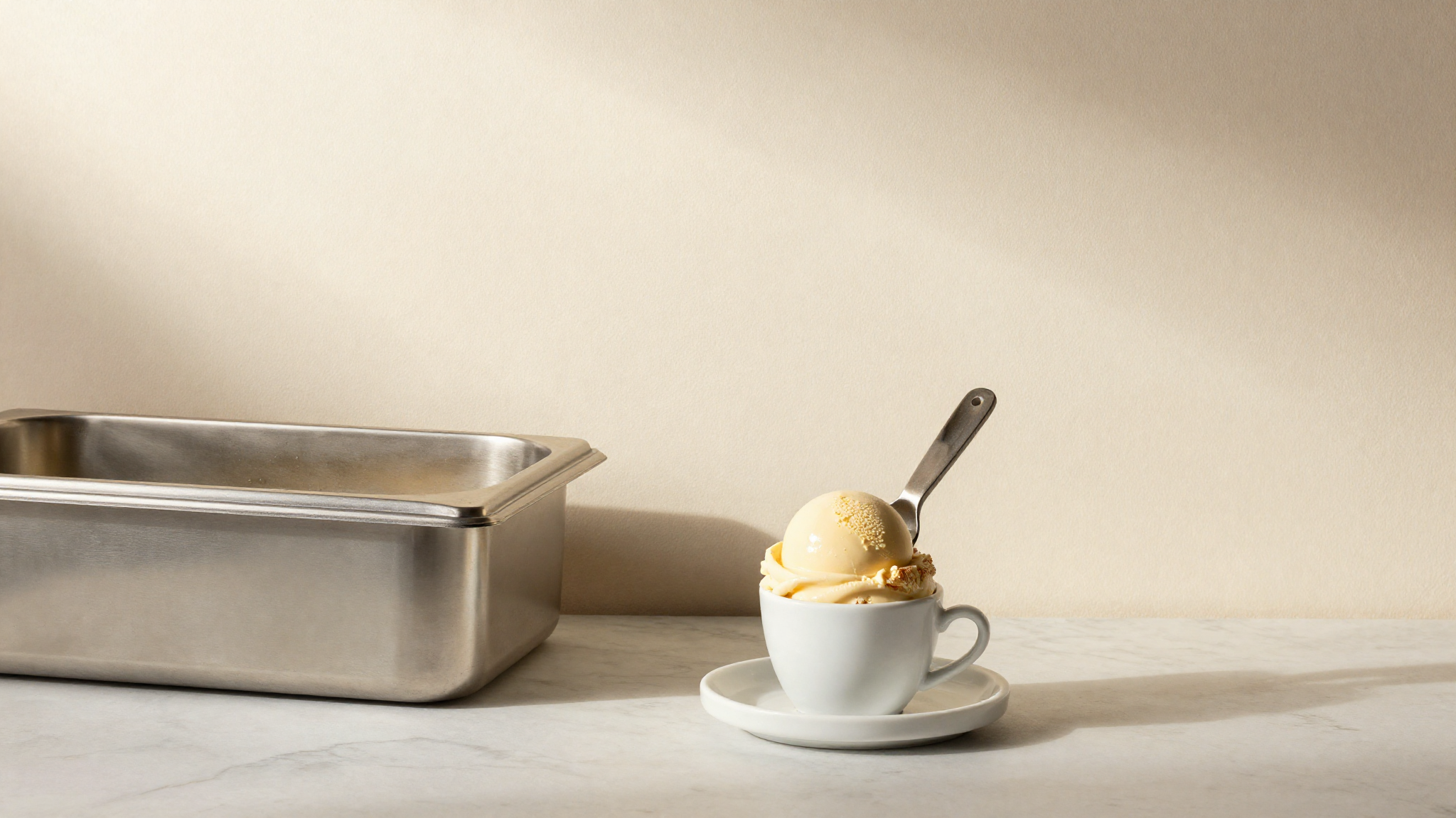 A vertical batch freezer mantecatore drawing a ribbon of fresh gelato into a stainless pan