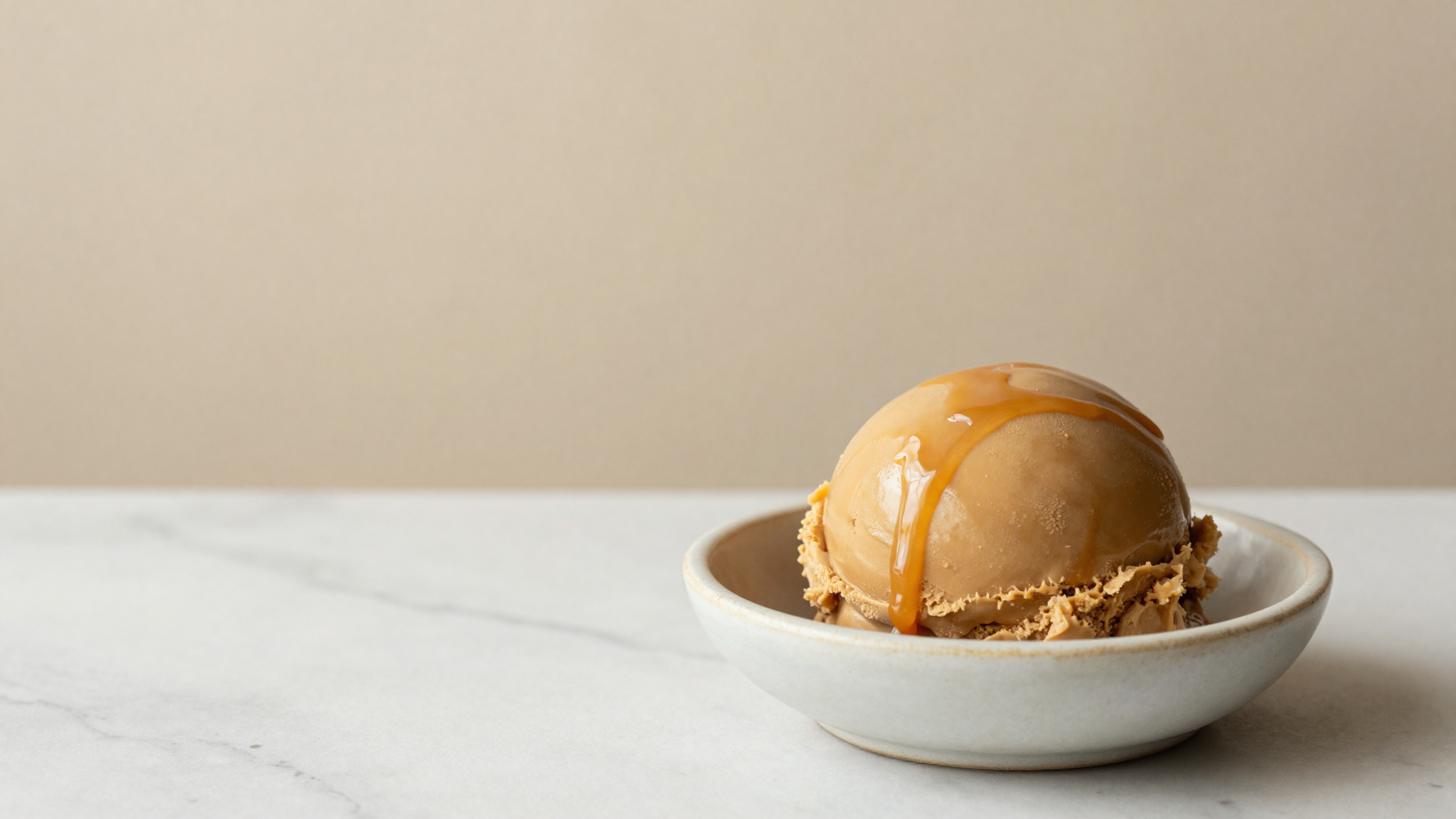 A close scoop of miso caramel gelato showing a smooth dense body and glossy caramel ripple