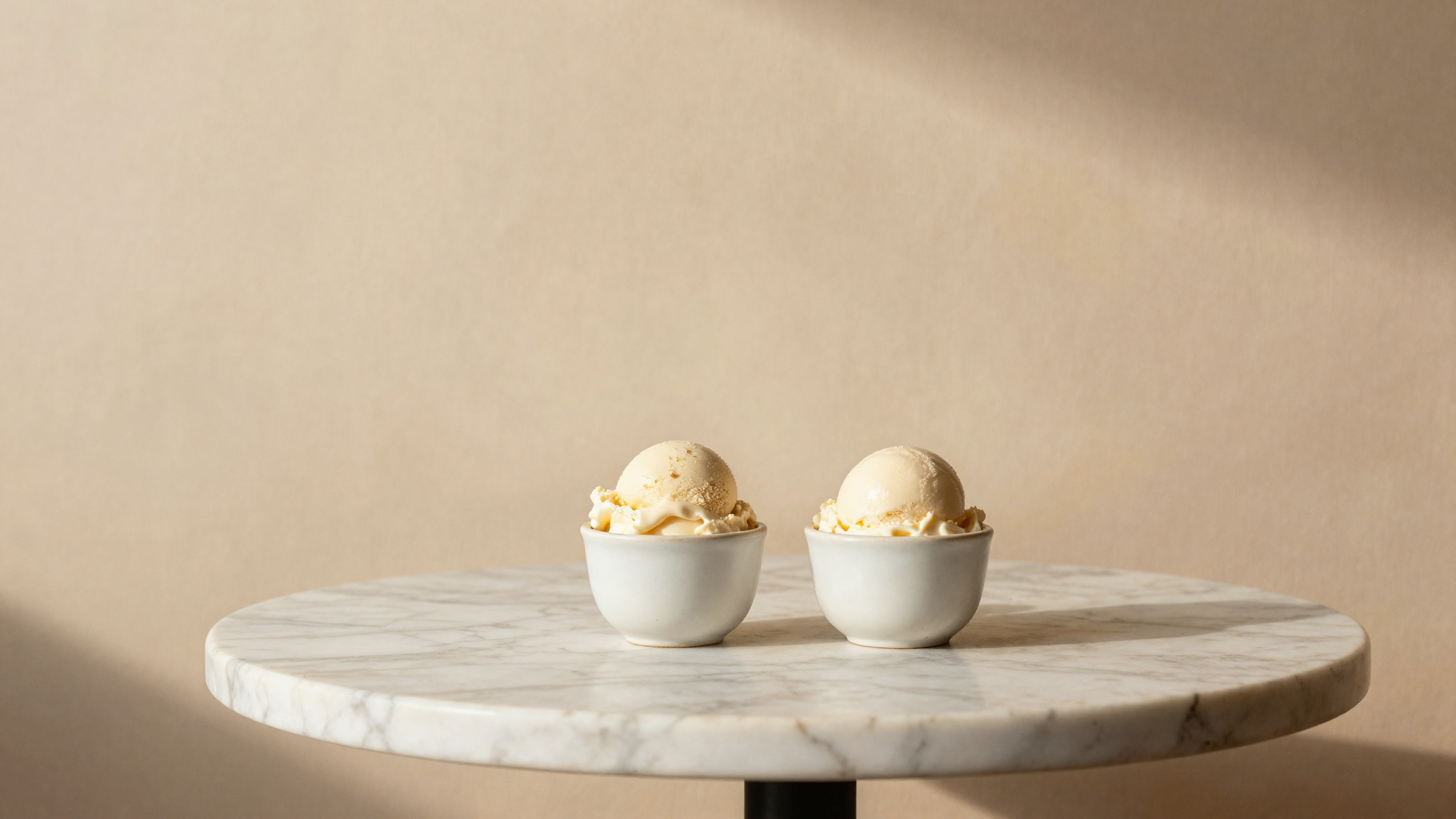 Two small ceramic cups of gelato side by side on a marble cafe table