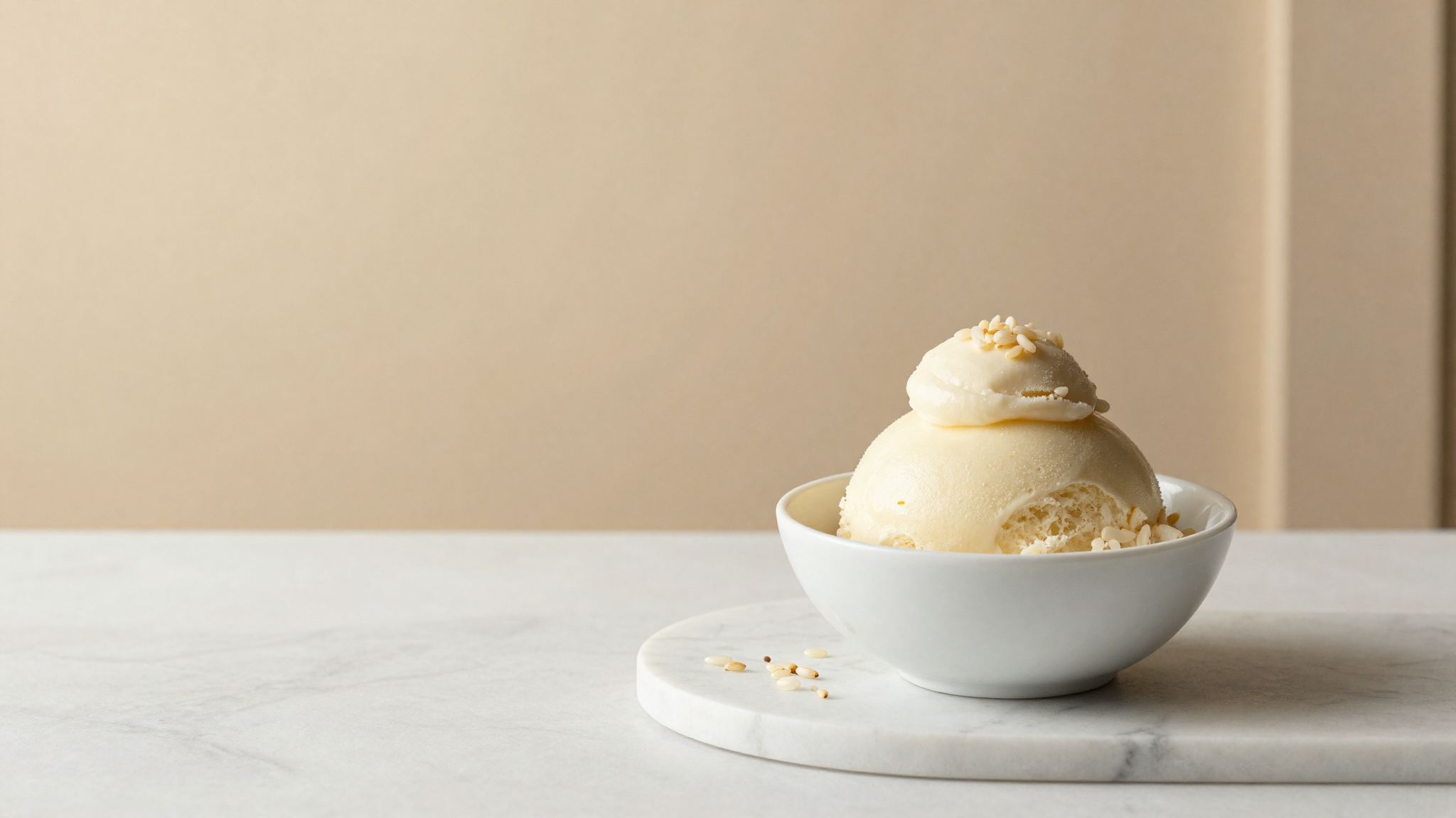 A finished quenelle of pale vegan rice milk gelato in a ceramic bowl garnished with rice