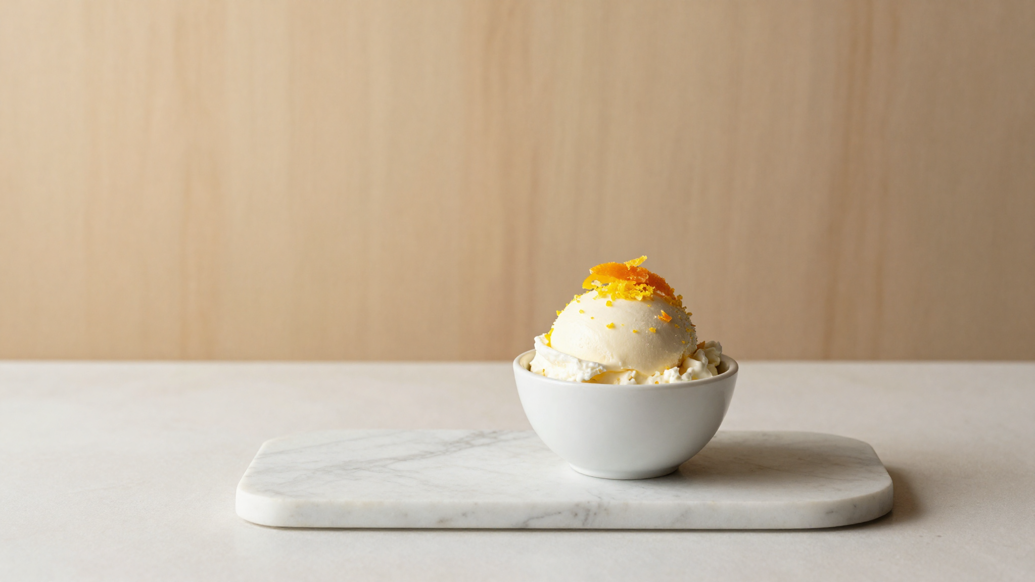 Sicilian ricotta gelato in a small ceramic cup with lemon zest on marble