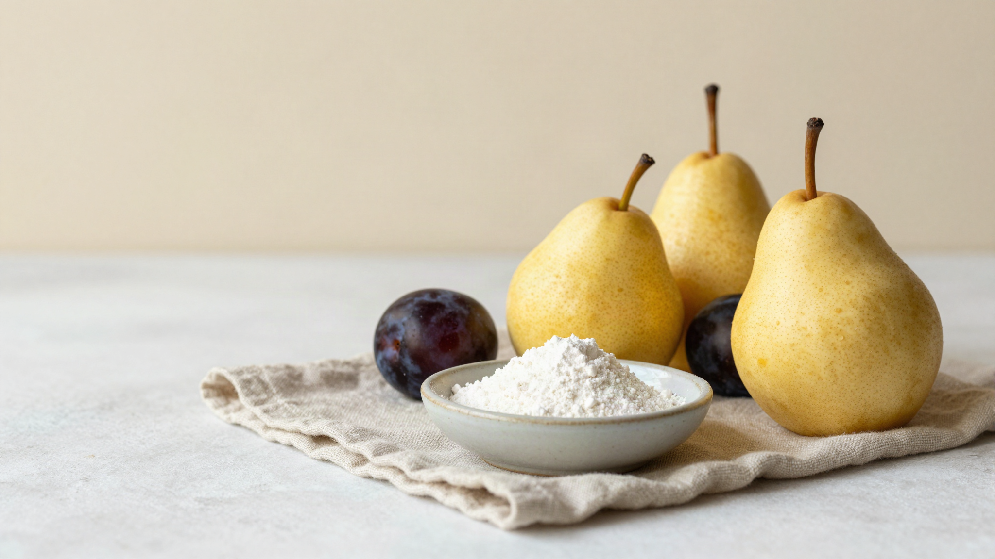 Ripe pears and dark plums on light linen beside a ceramic bowl of fine white polyol powder