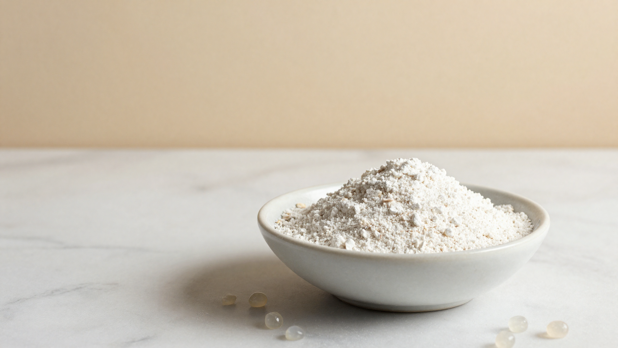 A bowl of fine white tapioca starch powder with tapioca pearls on marble