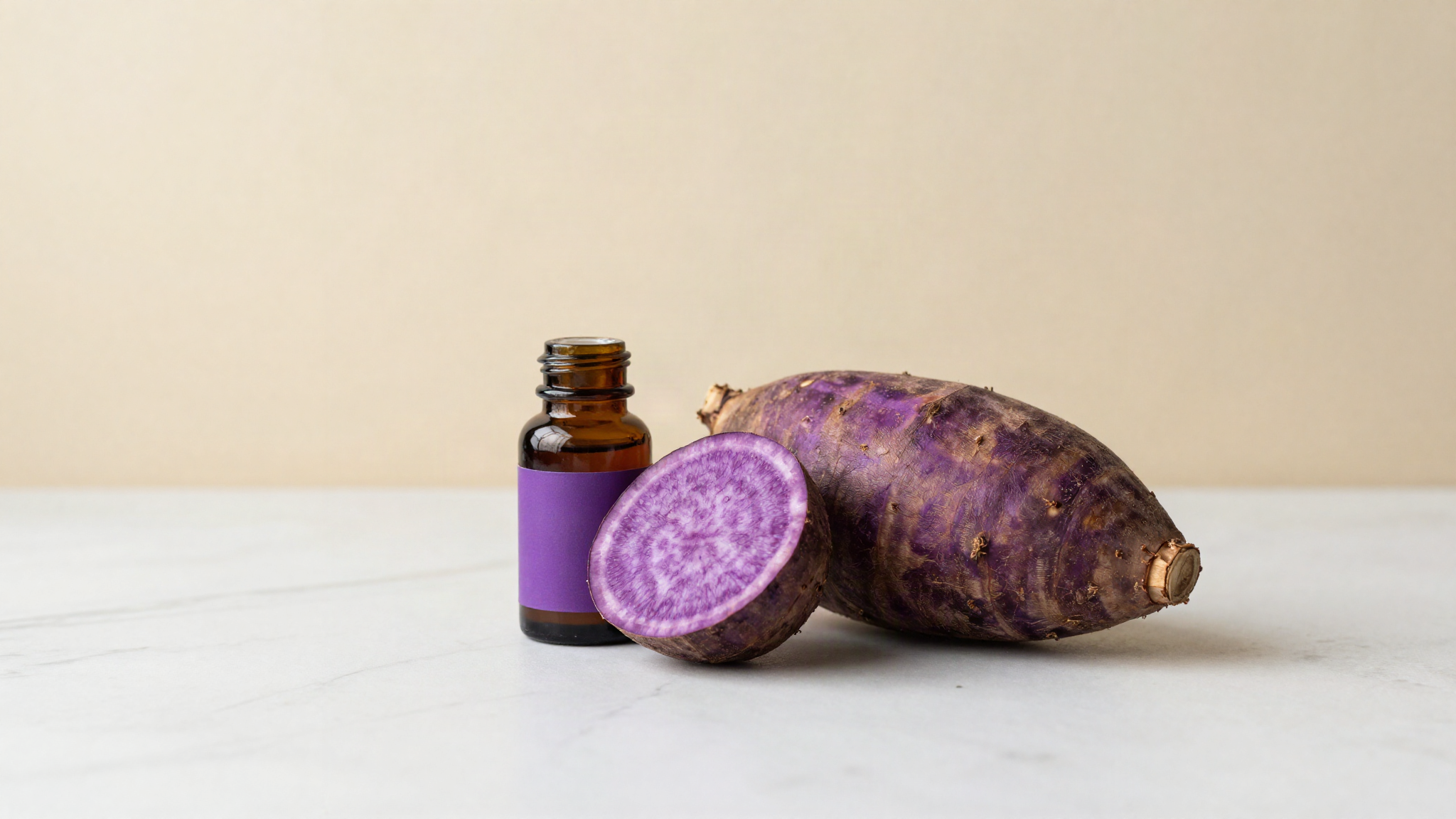 A fresh purple ube yam cut open beside a small bottle of ube extract on marble