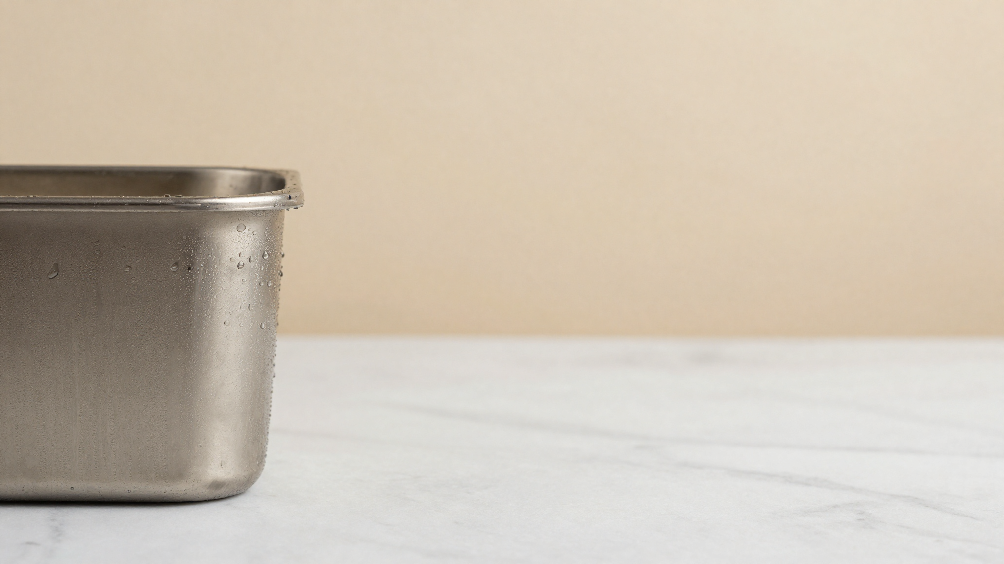 Condensation and fine frost beading on a chilled stainless steel gelato container