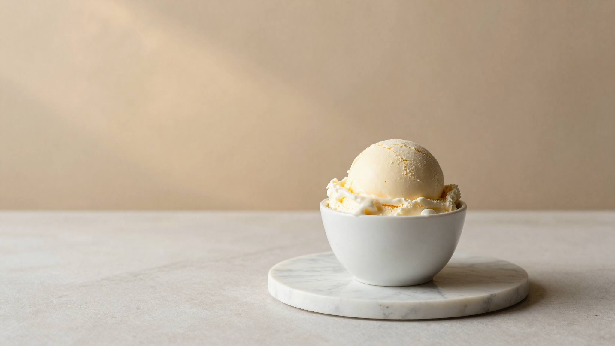 Scoop of italian gelato in a white ceramic cup on marble showing creamy dense dairy structure