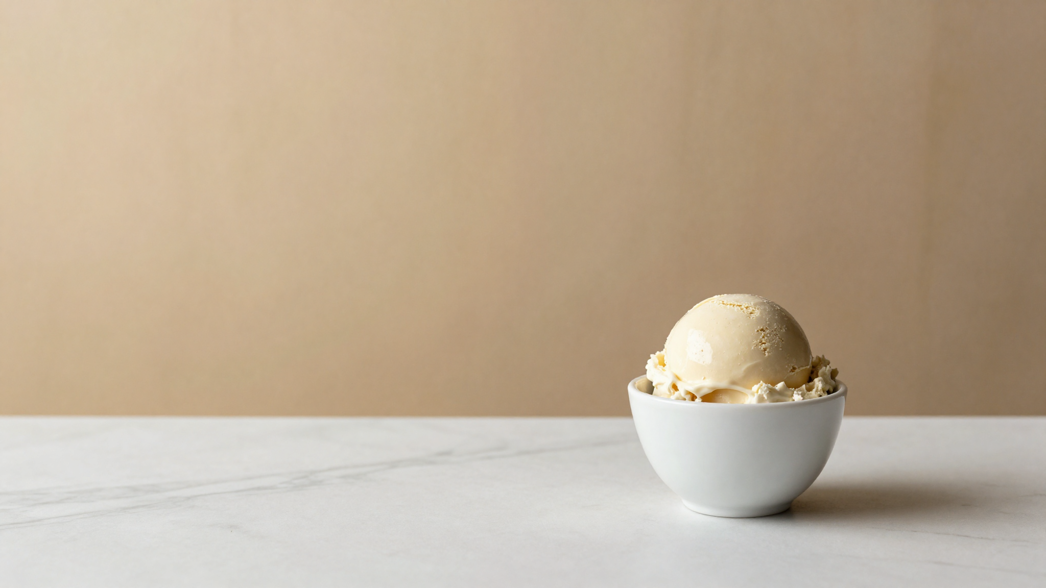 A scoop of pale ivory white chocolate gelato in a ceramic cup