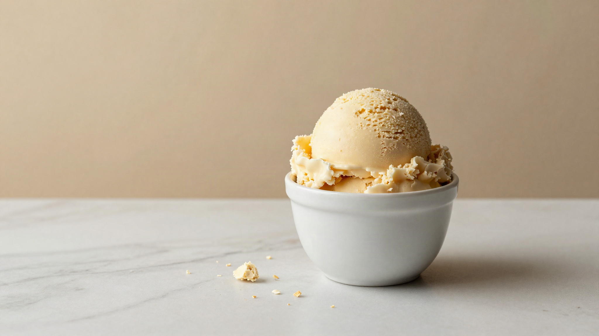 A scoop of gelato breaking into short crumbly flakes in a white ceramic cup