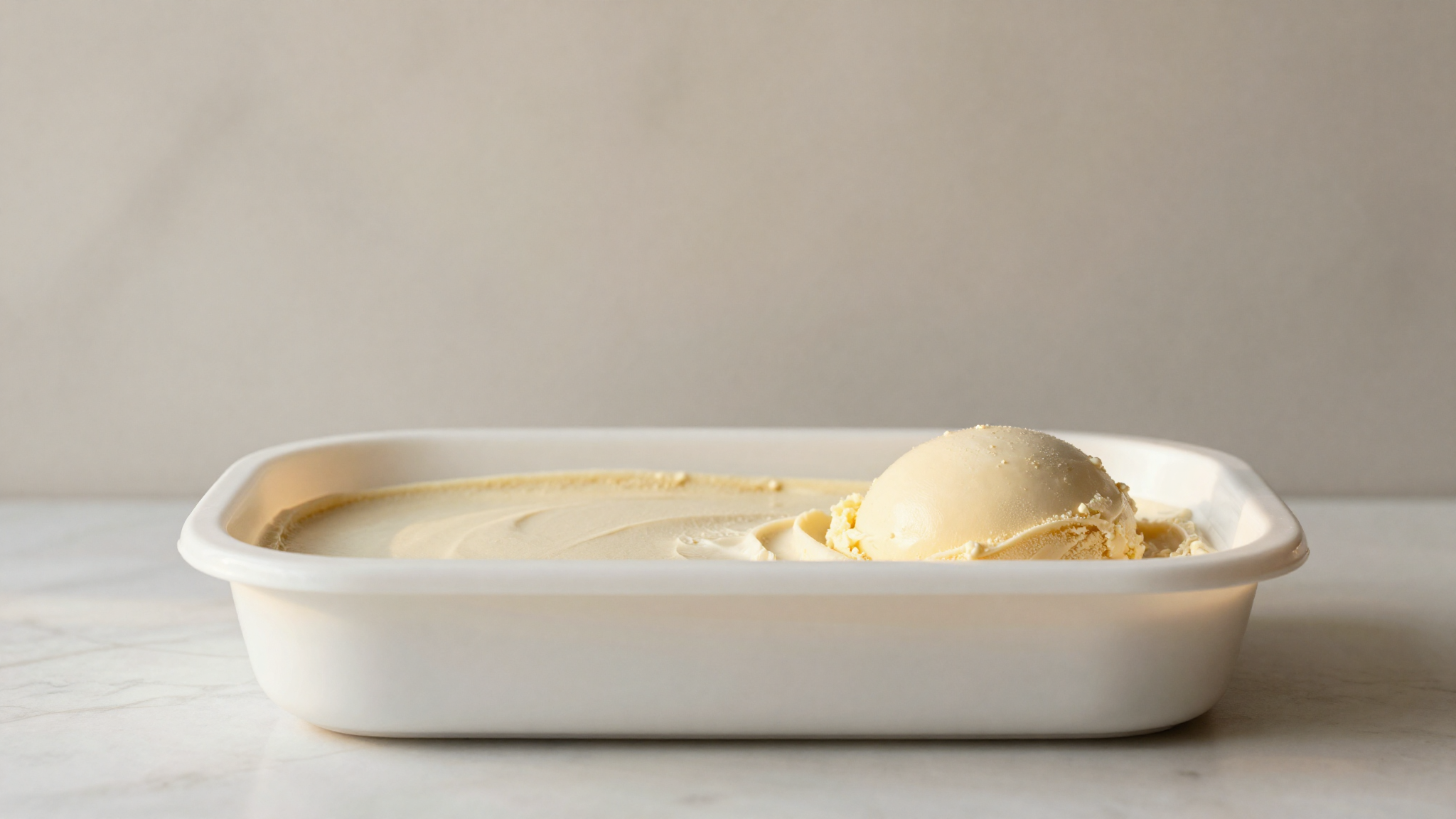 A cleanly filled, level tub of freshly hardened gelato on marble