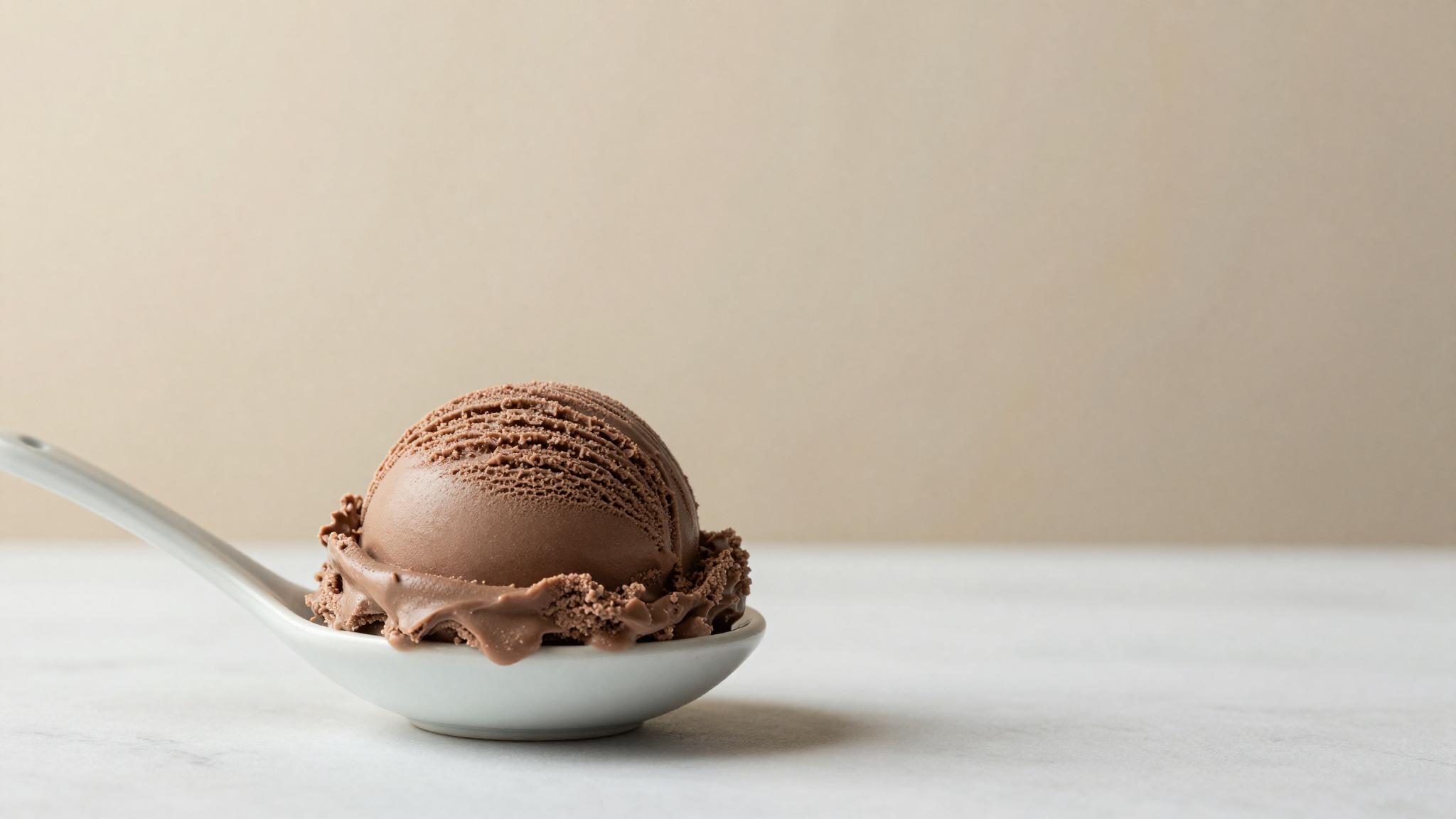 A soft elegant scoop of chocolate italian gelato lifted easily onto a ceramic spoon showing perfect creamy elastic texture