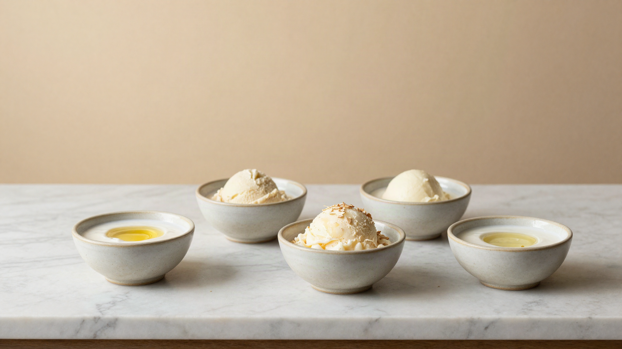 Coconut cream, oat milk and refined coconut oil in small ceramic bowls on a marble counter