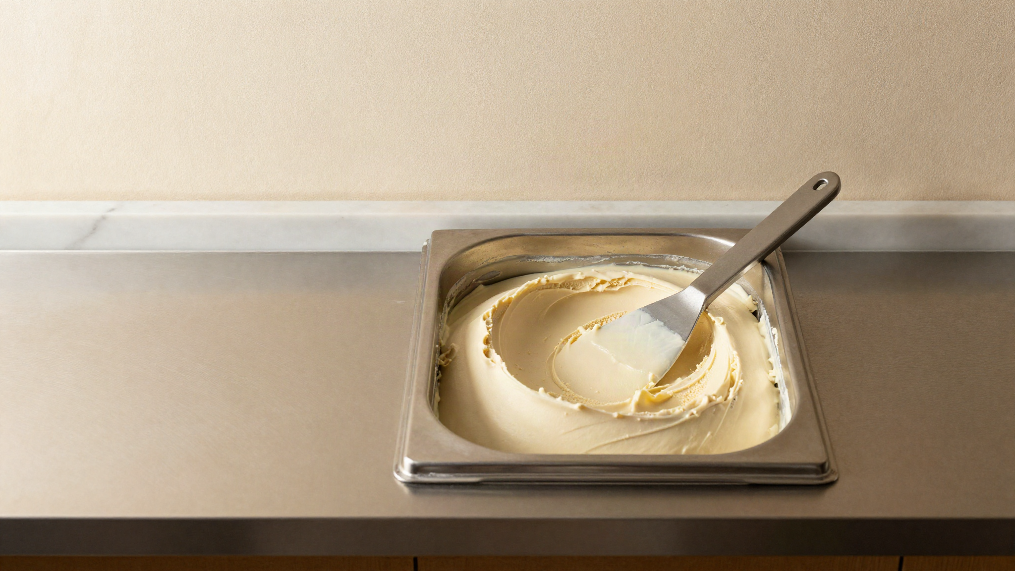 A stainless gelato pan of smooth plant-based gelato with a clean spatula sweep